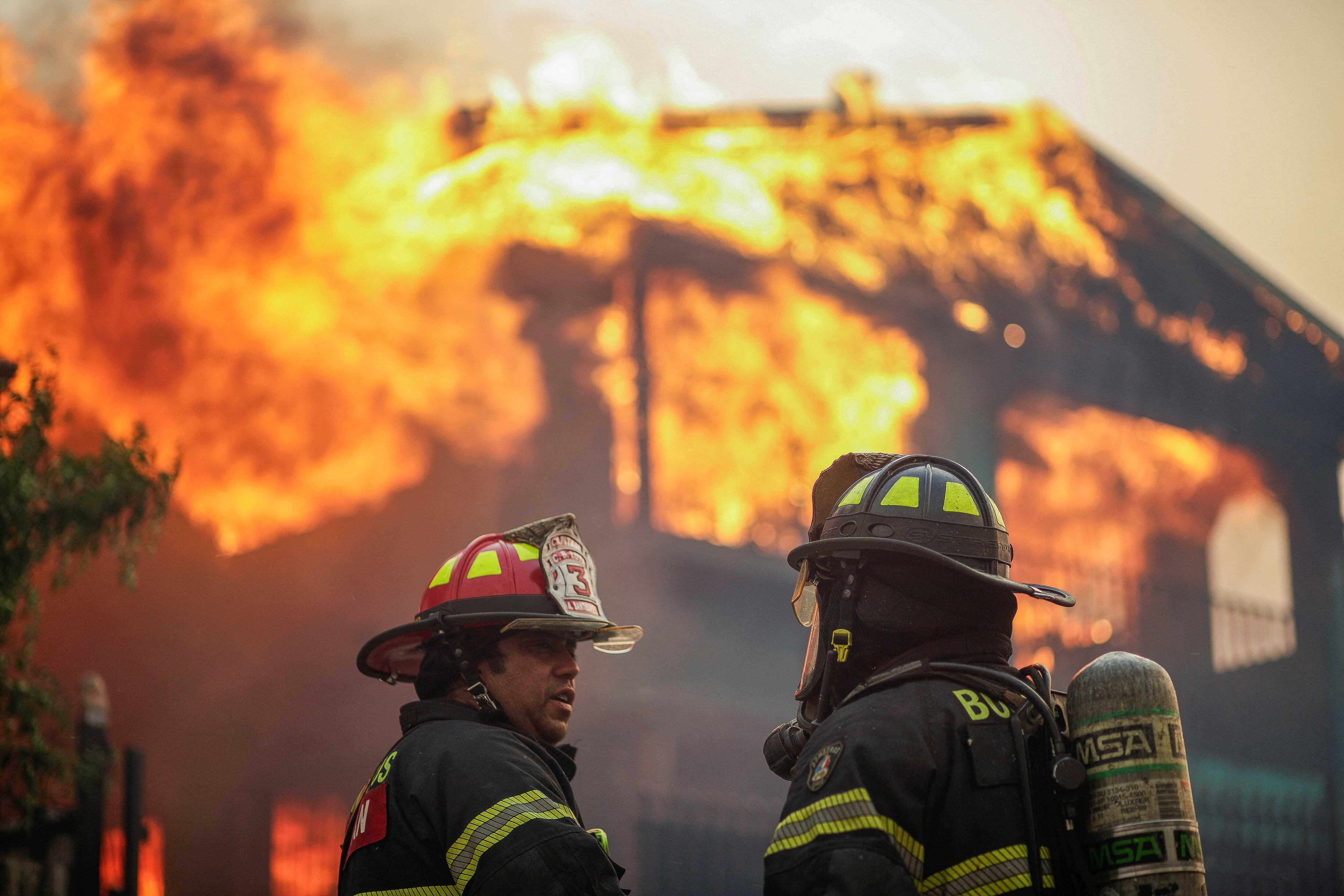 Bomberos frente a un edificio en llamas tras un incendio forestal en la región del Biobío, donde, según medios locales, múltiples incendios forestales provocaron evacuaciones de emergencia, en Concepción, Chile, el 18 de enero de 2026. REUTERS/Juan Gonzalez
