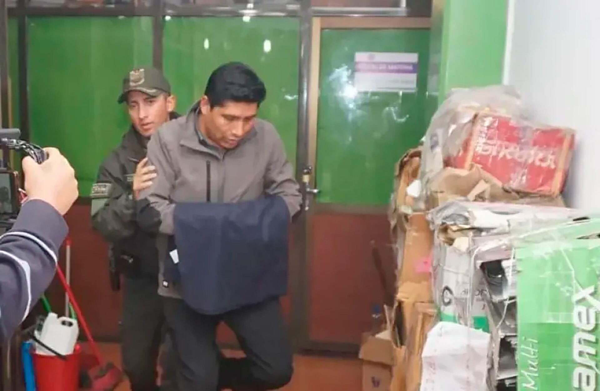 El ex gerente de la empresa estatal de alimentos de Bolivia escoltado por policías tras su detención en octubre de 2025.
Foto: Unitel