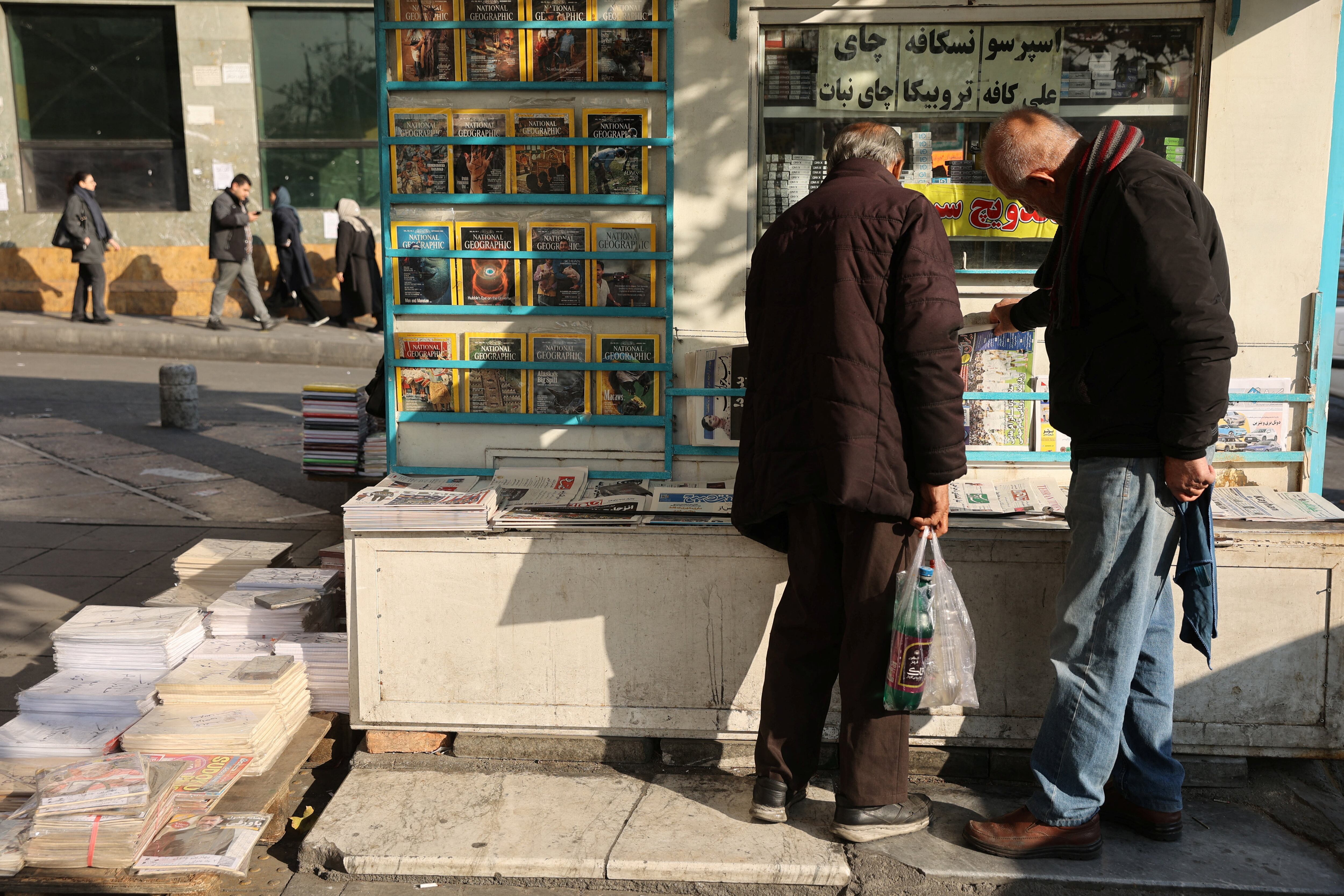 Hombres iraníes leen periódicos en una calle, mientras estallan protestas por el desplome del valor de la moneda, en Teherán, Irán, 5 de enero de 2026 (Majid Asgaripour/WANA (Agencia de Noticias de Asia Occidental) vía REUTERS )