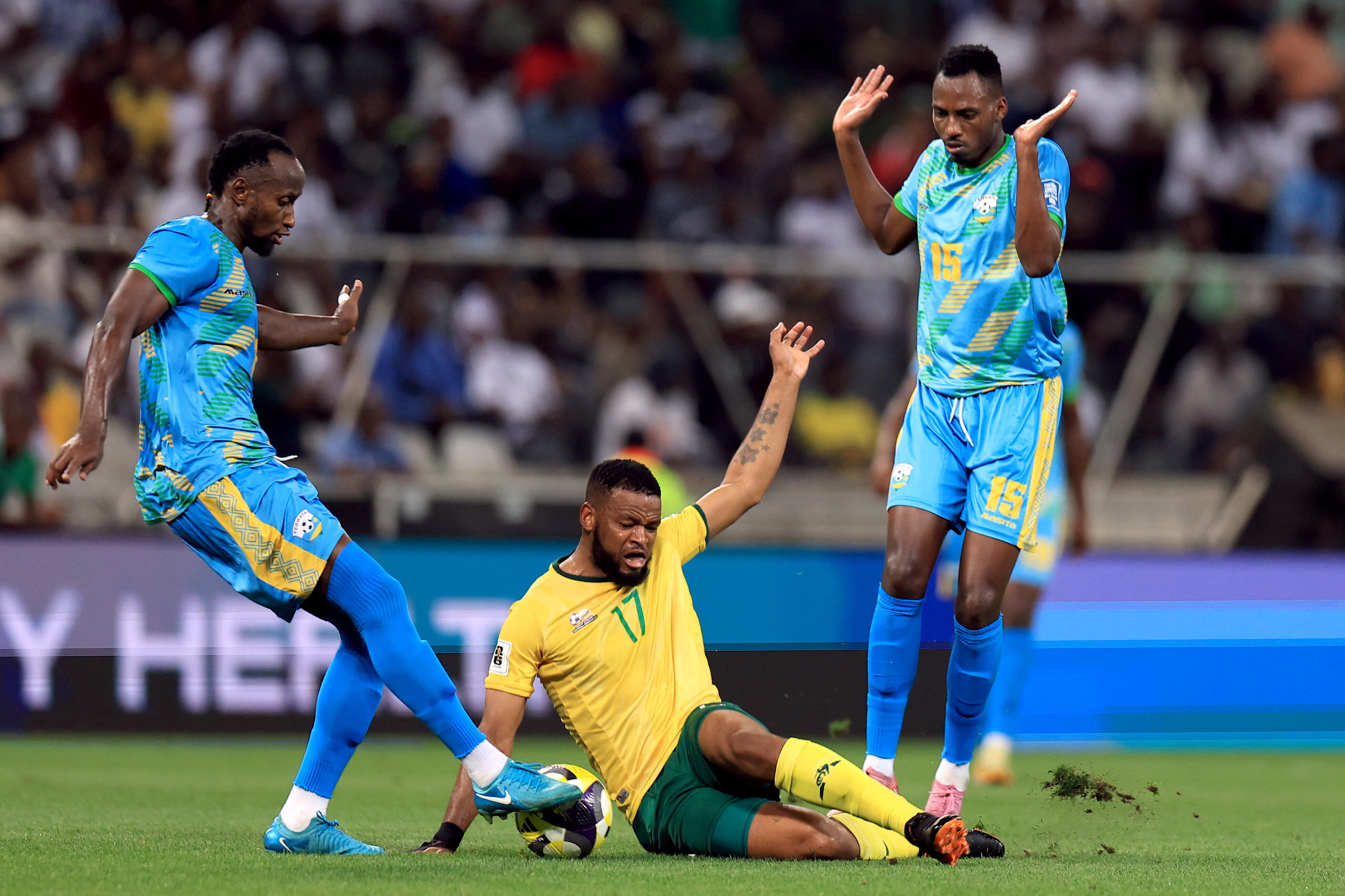 Un jugador de Sudáfrica pelea la pelota con dos rivales de Ruanda en el piso (Crédito: Reuters/Esa Alexander)