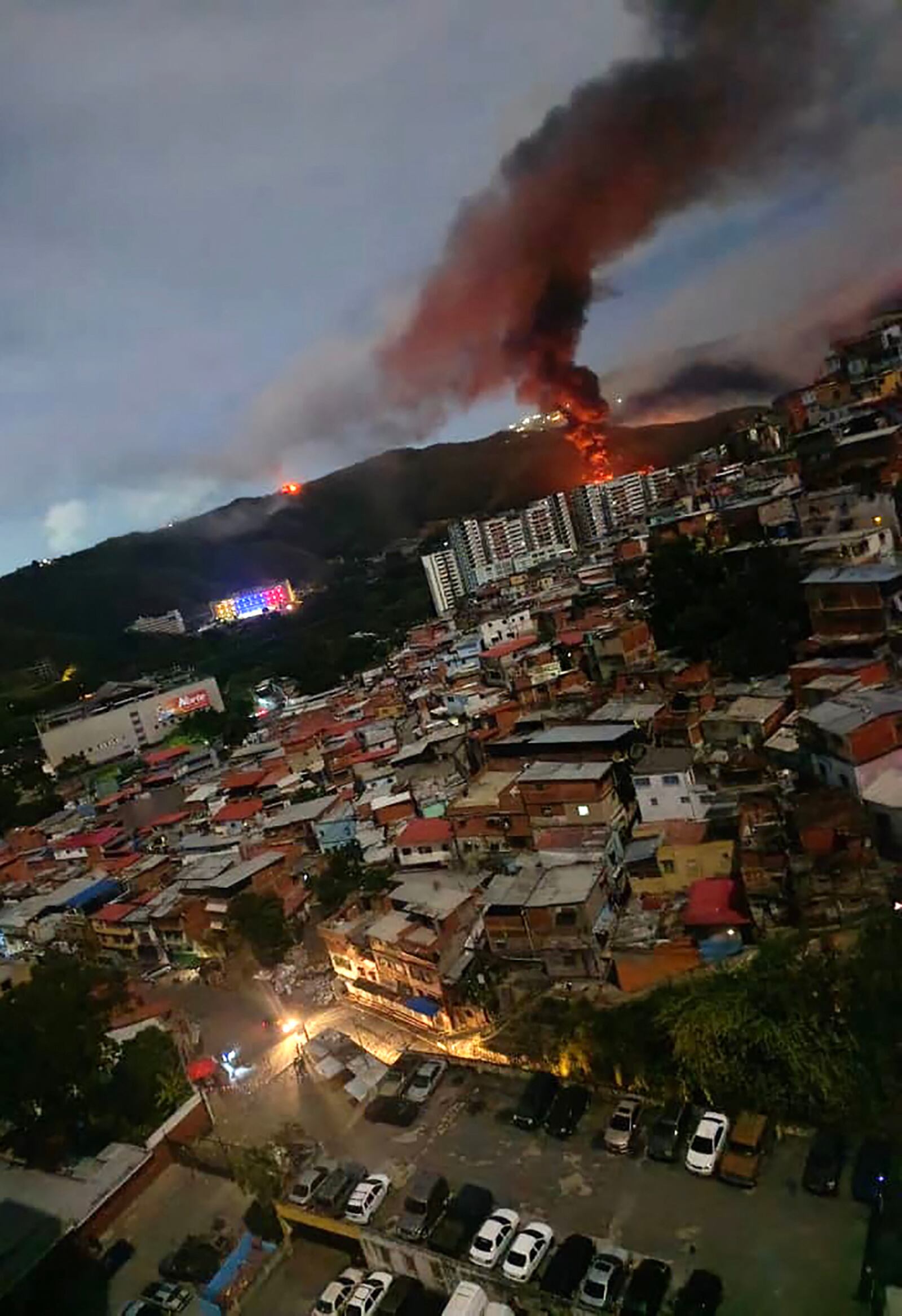 Un incendio en Fuerte Tiuna, el mayor complejo militar de Venezuela, es visto a distancia tras una serie de explosiones en Caracas el 3 de enero de 2026. El ejército de Estados Unidos estuvo detrás de una serie de ataques contra la capital venezolana, Caracas, el sábado, según informaron medios estadounidenses. La Casa Blanca y el Pentágono no han comentado sobre las explosiones ni sobre los reportes de aeronaves sobre la ciudad. Los medios estadounidenses CBS News y Fox News citaron a funcionarios no identificados del gobierno de Trump confirmando que fuerzas estadounidenses estuvieron involucradas. (AFP)