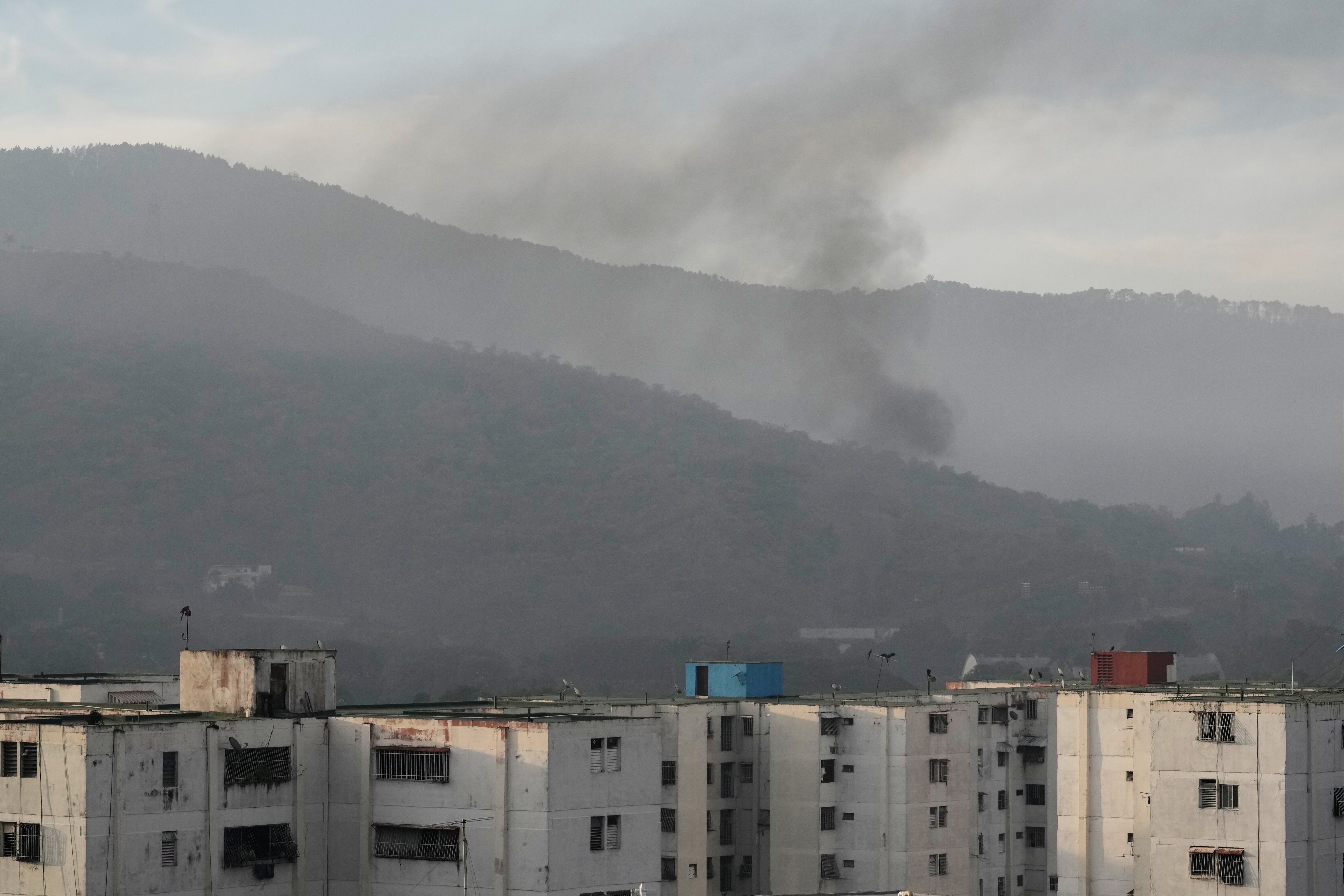 El humo se eleva desde Fuerte Tiuna, la principal guarnición militar en Caracas, Venezuela, después de que se escucharan múltiples explosiones y aeronaves sobrevolaran la zona, el sábado 3 de enero de 2026. (AP/Matias Delacroix)