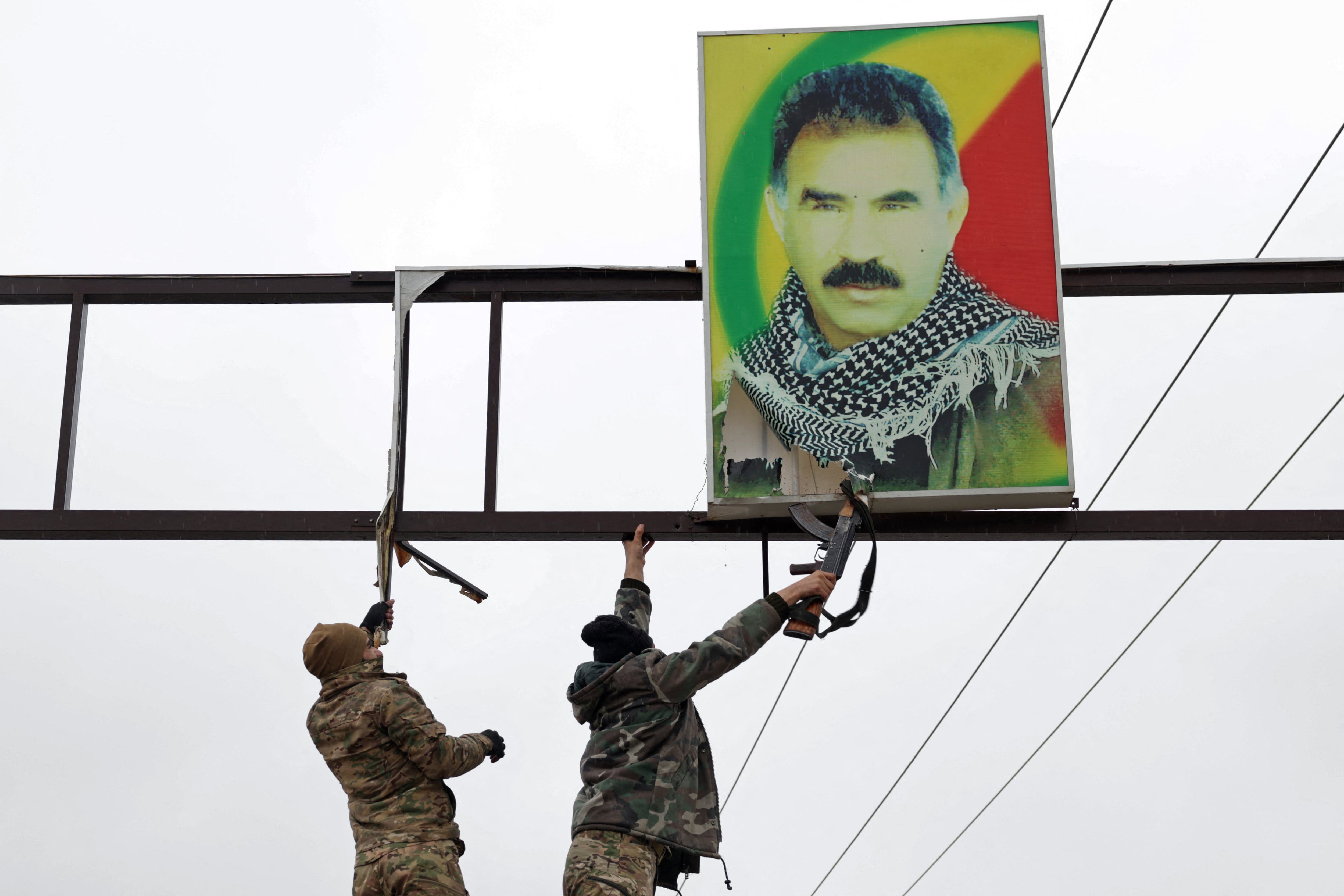 Personal del ejército sirio se prepara para retirar un retrato de Abdullah Öcalan en Tabqa, provincia de Raqa, enero de 2026. Las oficinas de la administración autónoma cerraron sus puertas y retiraron los símbolos del líder del PKK mientras el Rojava entraba en su fase de liquidación tras 14 años. (Bakr ALkasem / AFP)