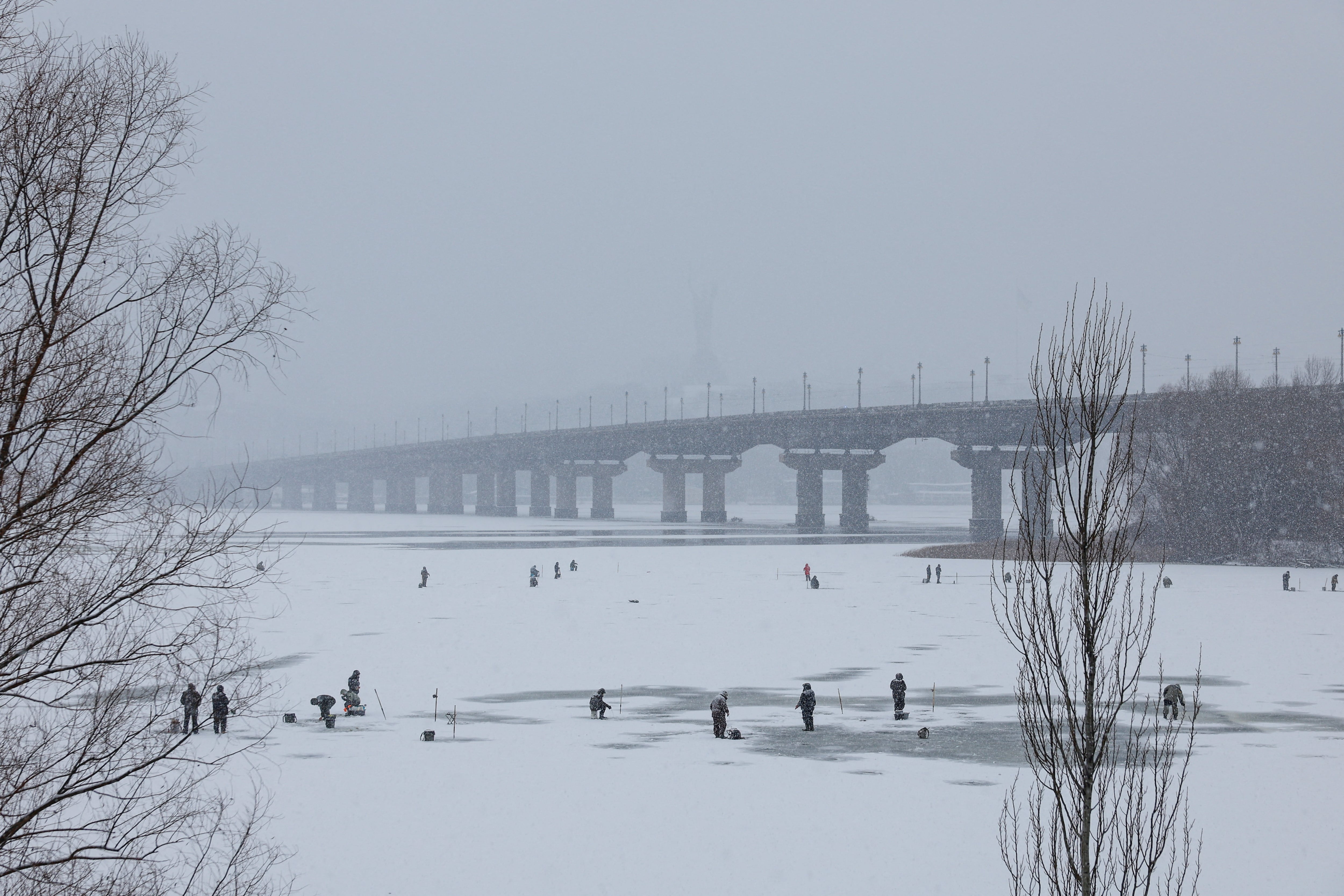 La gente pesca en el río Dnipro, congelado durante una nevada, en medio del ataque ruso a Ucrania (REUTERS/Valentyn Ogirenko)