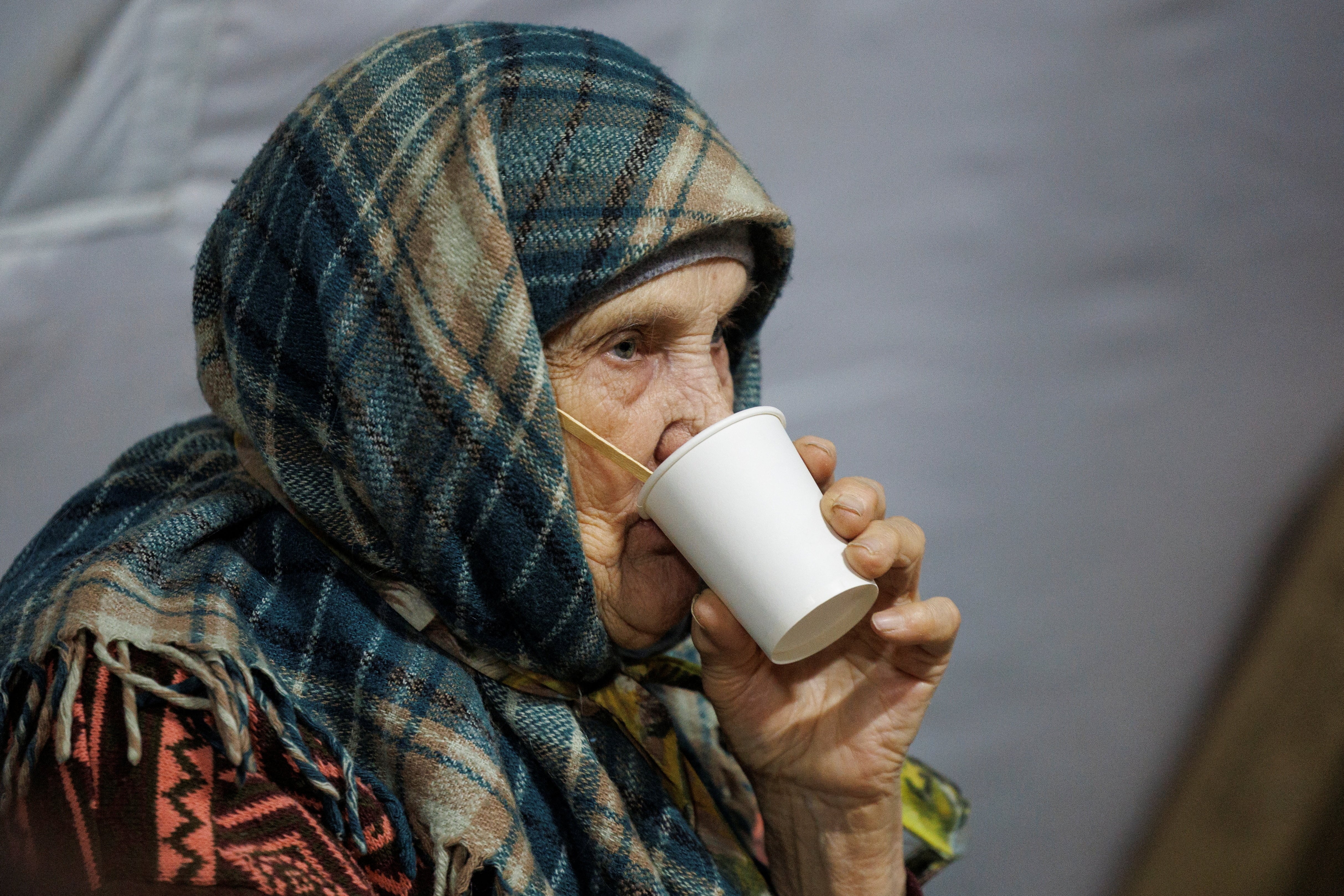 Una anciana busca refugio y una bebida caliente durante el ataque ruso con misiles y drones en la capital ucraniana. (REUTERS/Valentyn Ogirenko)