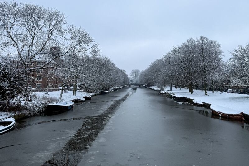 Canal de un río cubierto de hielo en Ámsterdam, en medio de interrupciones del tráfico aéreo, ferroviario y vial causadas por las nevadas, ya que cientos de vuelos fueron cancelados y los trenes se detuvieron, en Países Bajos, el 5 de enero de 2026 (REUTERS/Charlotte Van Campenhout)
