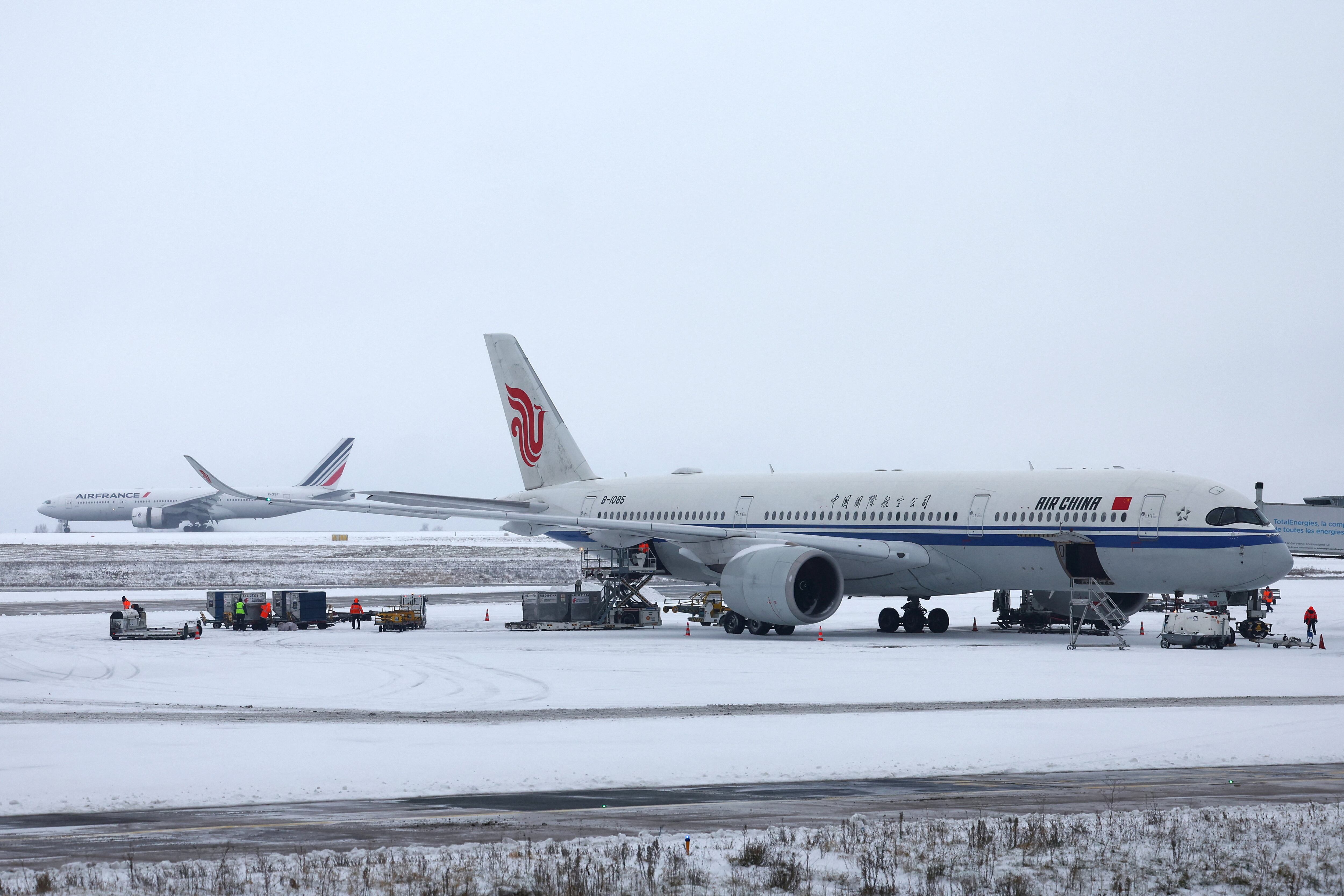 Un avión de Air China se ve en la pista cubierta de nieve en la Terminal 1 de París CDG del Aeropuerto París-Charles de Gaulle, en Roissy-en-France, cerca de París, mientras el tráfico se interrumpe y algunos vuelos se cancelan debido al clima invernal con nieve y bajas temperaturas en parte del país, Francia, 7 de enero de 2026 (REUTERS/Abdul Saboor)