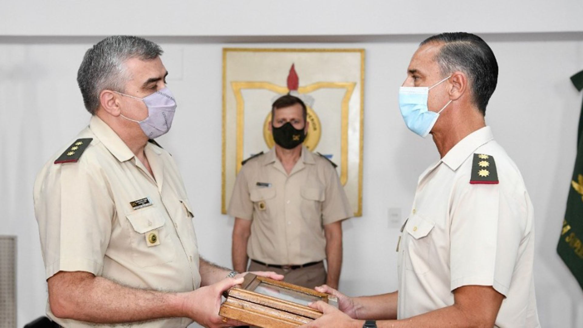 Diego Gasparutti, exdirector de la Escuela de Gendarmería, recibe un homenaje oficial de manos de otro oficial en una ceremonia