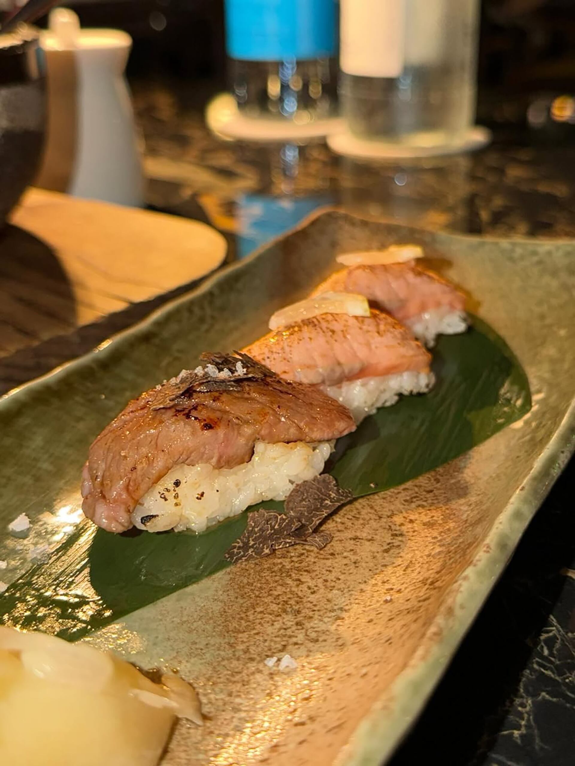 El plato principal parece ser una selección exquisita de nigiri presentado con salmón flameado