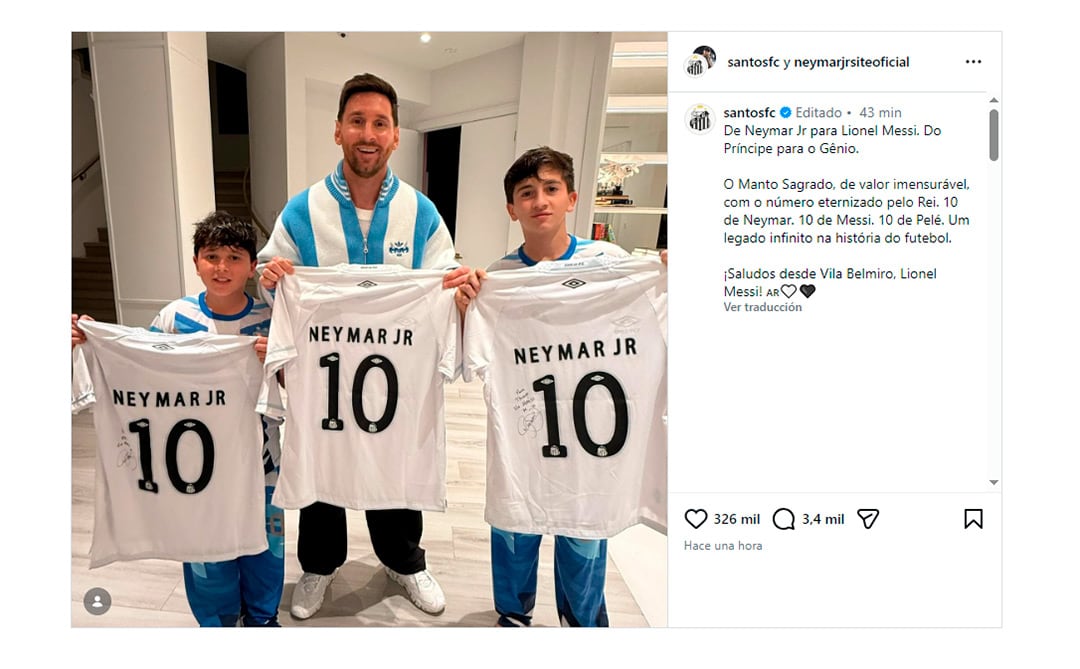 Lionel Messi y dos niños sonríen mientras sostienen tres camisetas blancas con el nombre 