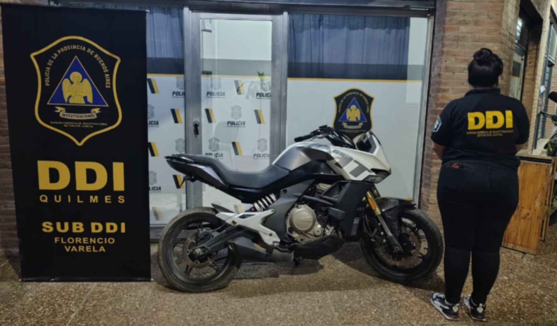 Una motocicleta secuestrada junto a una oficial de la DDI Quilmes, Sub DDI Florencio Varela, tras una serie de allanamientos que resultaron en detenidos y la incautación de armas. (DDI Quilmes)