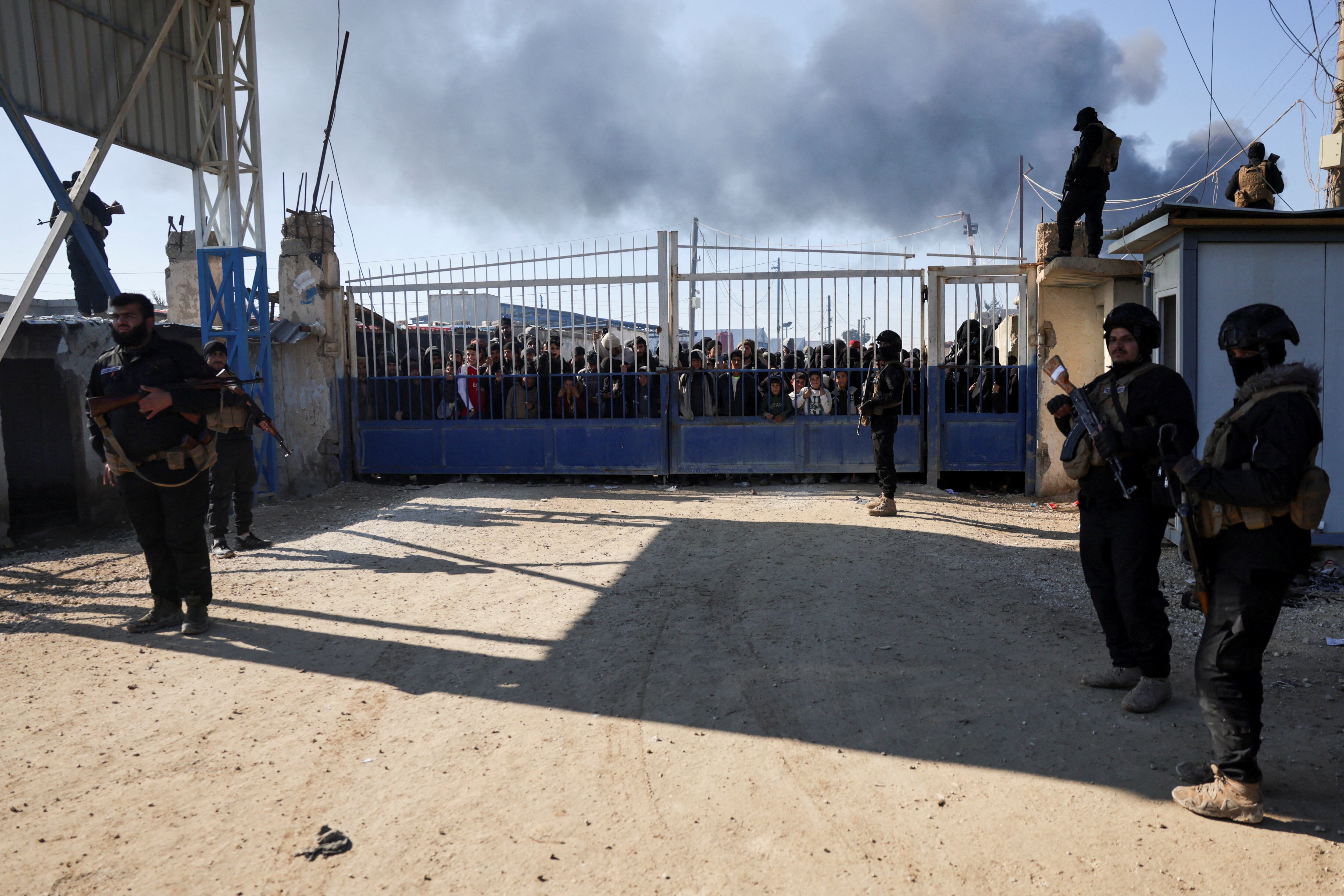 Miembros de las fuerzas de seguridad del gobierno sirio hacen guardia mientras un grupo de detenidos se reúne en el campamento de al-Hol después de que el gobierno tomó el control del mismo tras la retirada de las Fuerzas Democráticas Sirias (FDS), en Hasaka, Siria, el 21 de enero de 2026. REUTERS/Khalil Ashawi