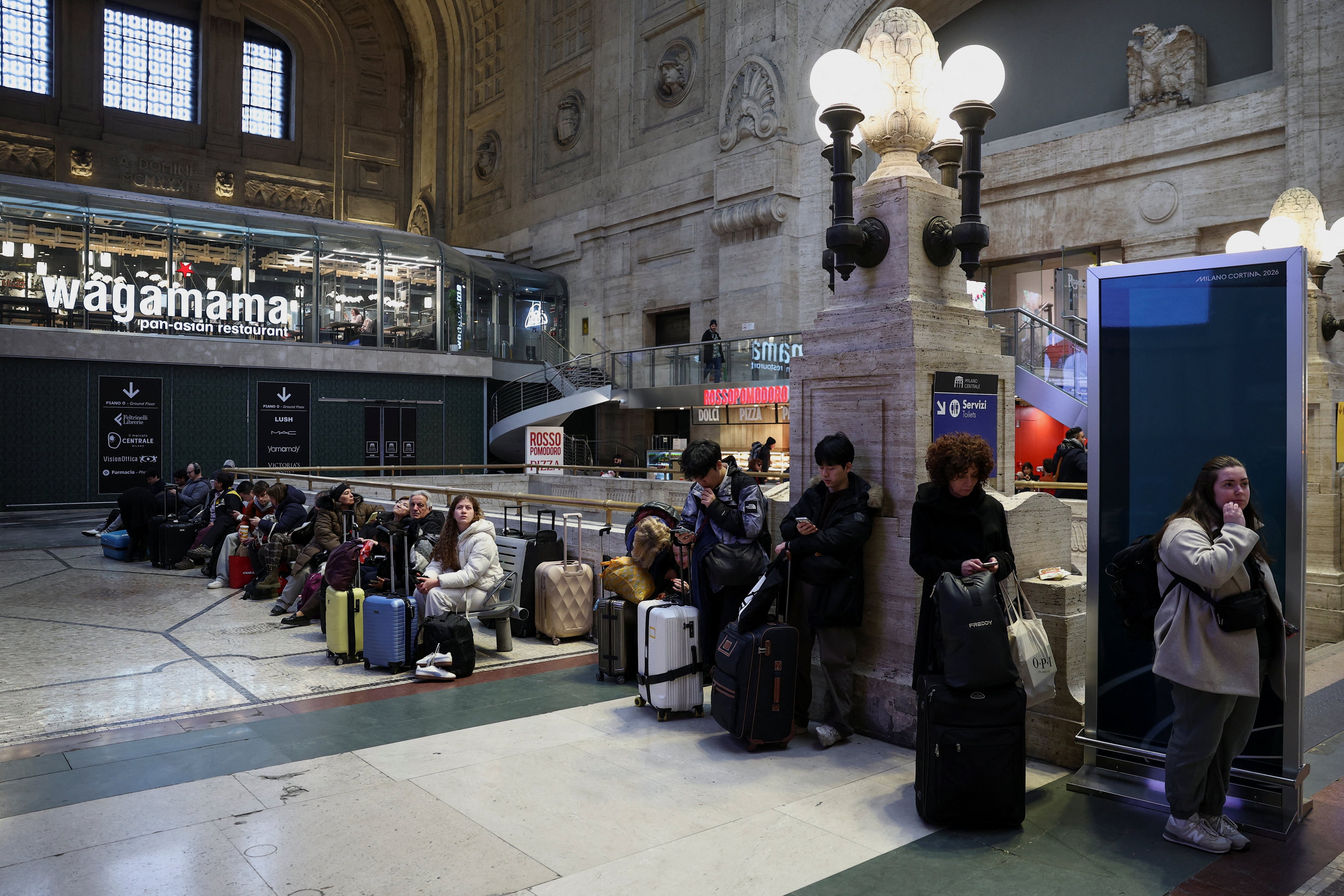 La gente espera en la estación de trenes de Milán, mientras la policía italiana investiga un posible sabotaje a los cables eléctricos cerca de la ciudad de Bologna, que han causado retrasos en gran parte de la red ferroviaria nacional (REUTERS/Guglielmo Mangiapane)