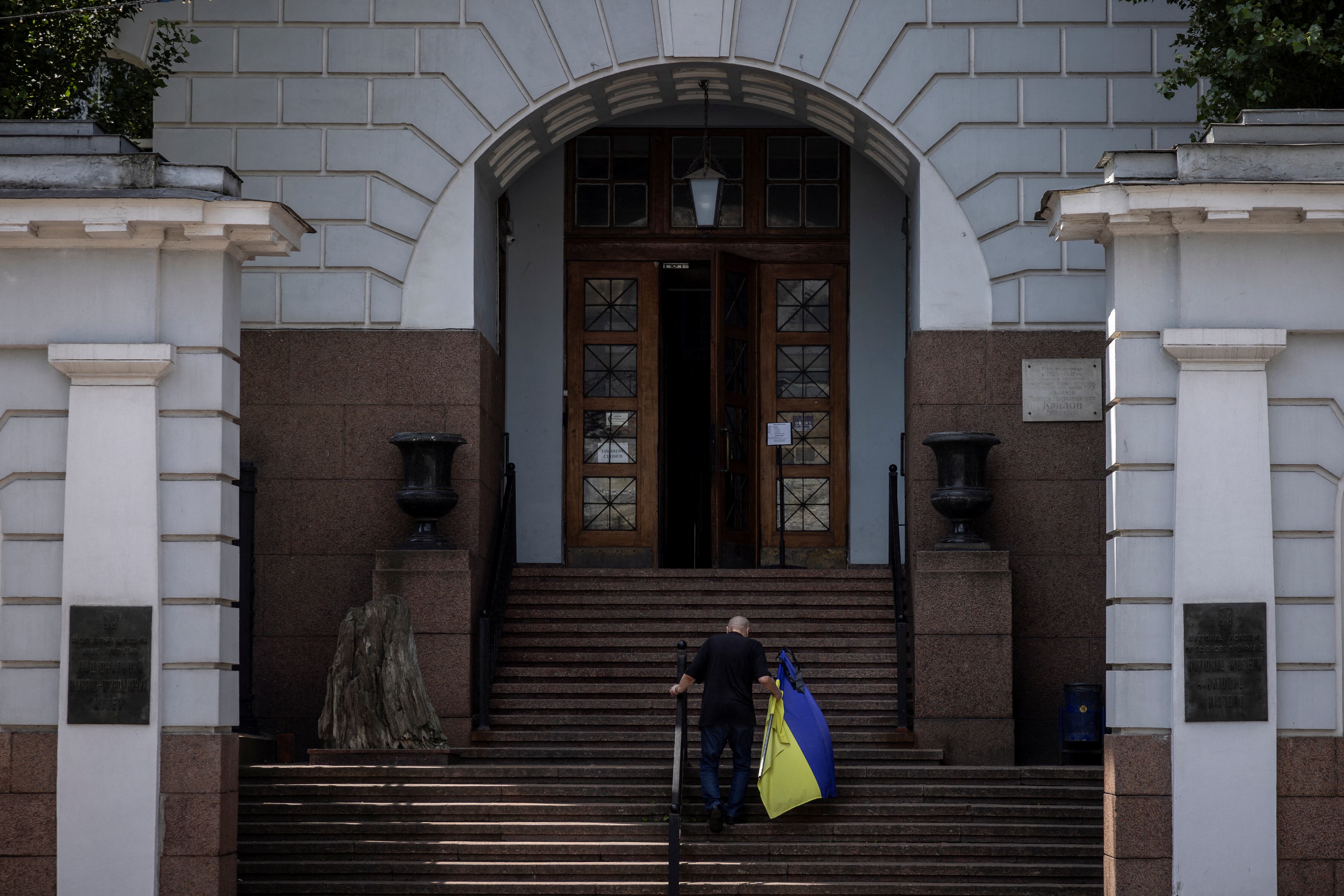 Un hombre lleva una bandera ucraniana al museo tras ataques rusos. Más de 1,680 sitios culturales han sido dañados durante la guerra (REUTERS/Thomas Peter)