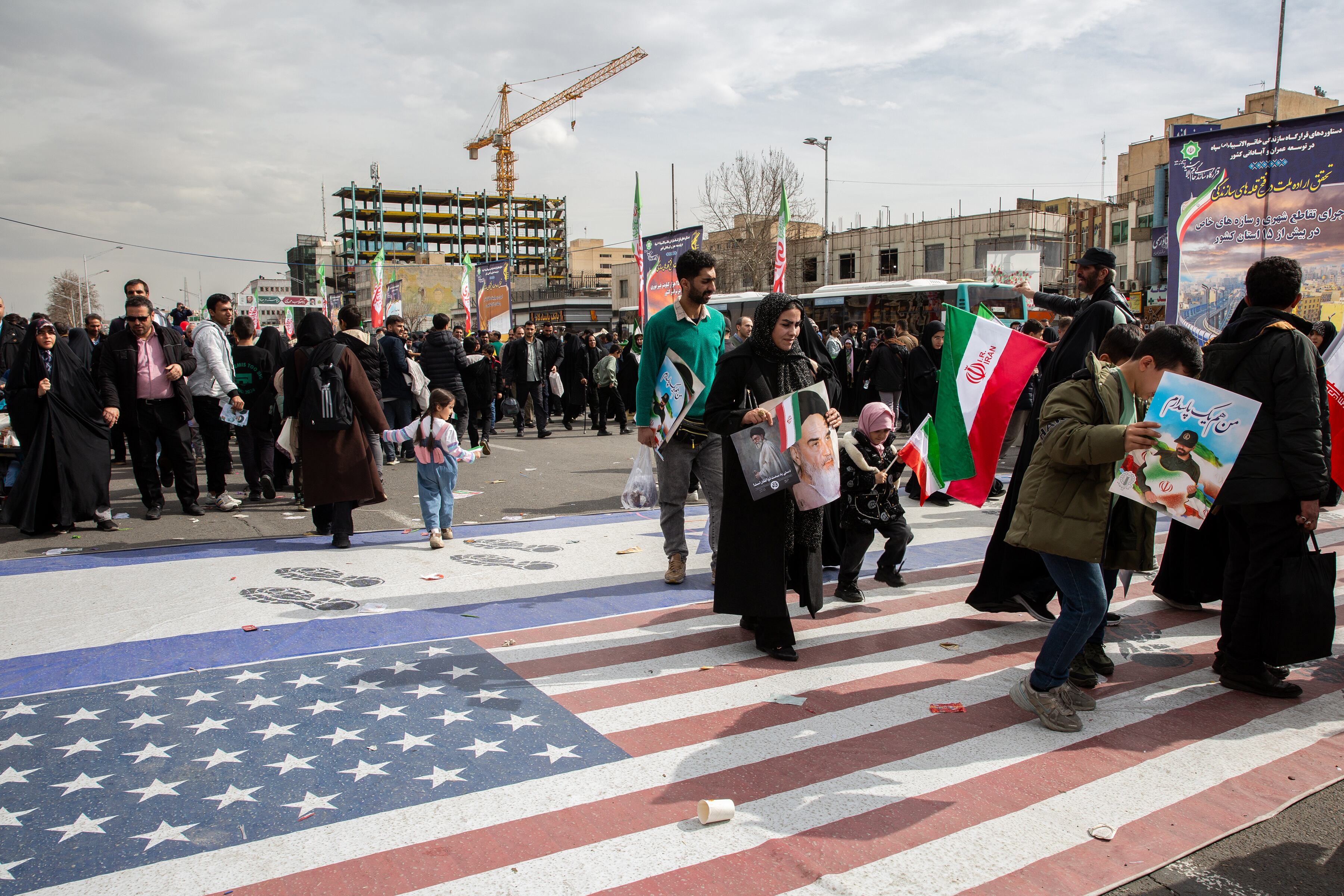 Personas en Teherán caminan sobre banderas estadounidenses e israelíes durante una marcha para conmemorar el 47 aniversario de la revolución islámica de Irán (Arash Khamooshi para The New York Times)
