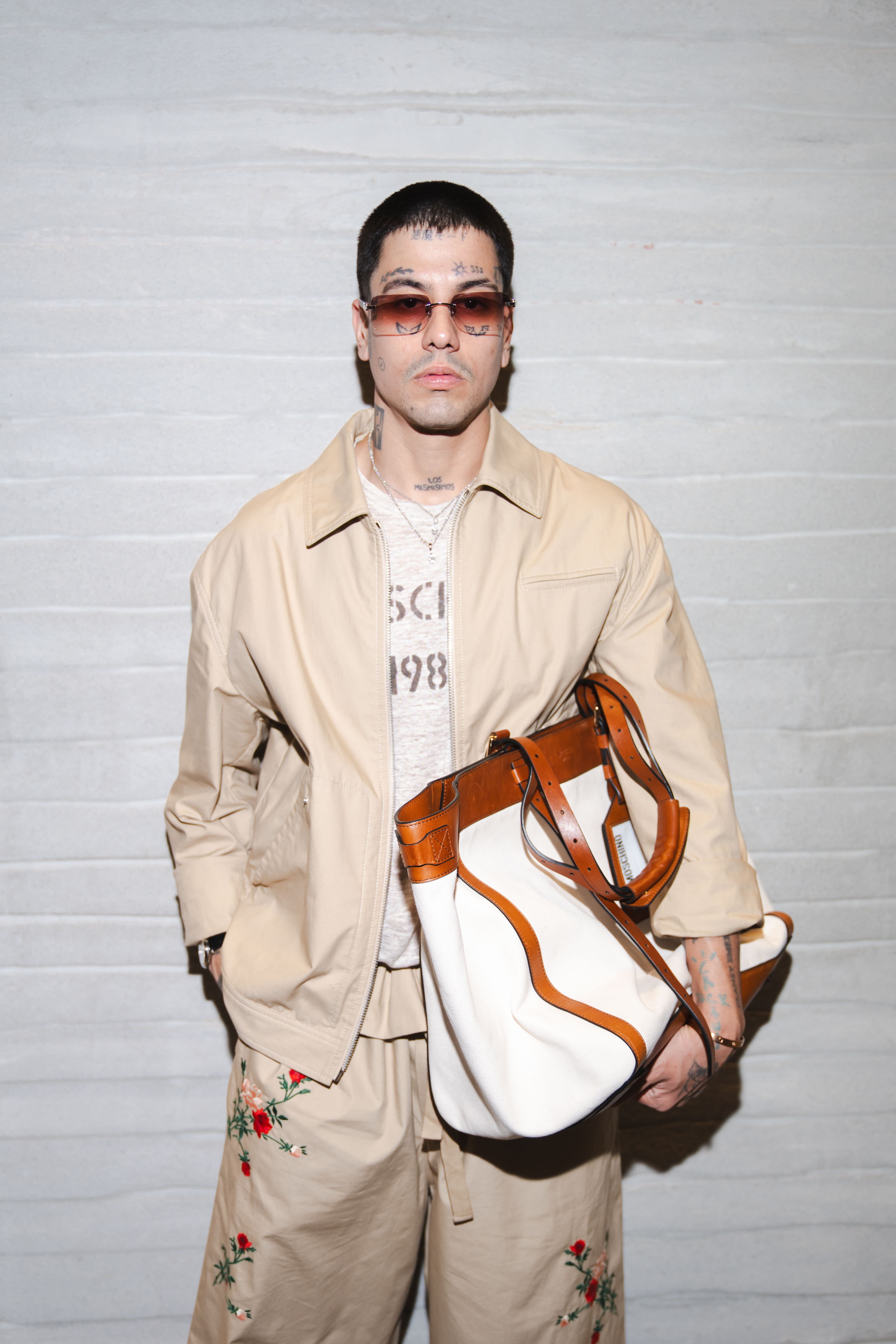 El artista Duki posa con un conjunto beige bordado y un bolso Moschino durante la Semana de la Moda de Milán, reafirmando su presencia en el mundo de la moda
