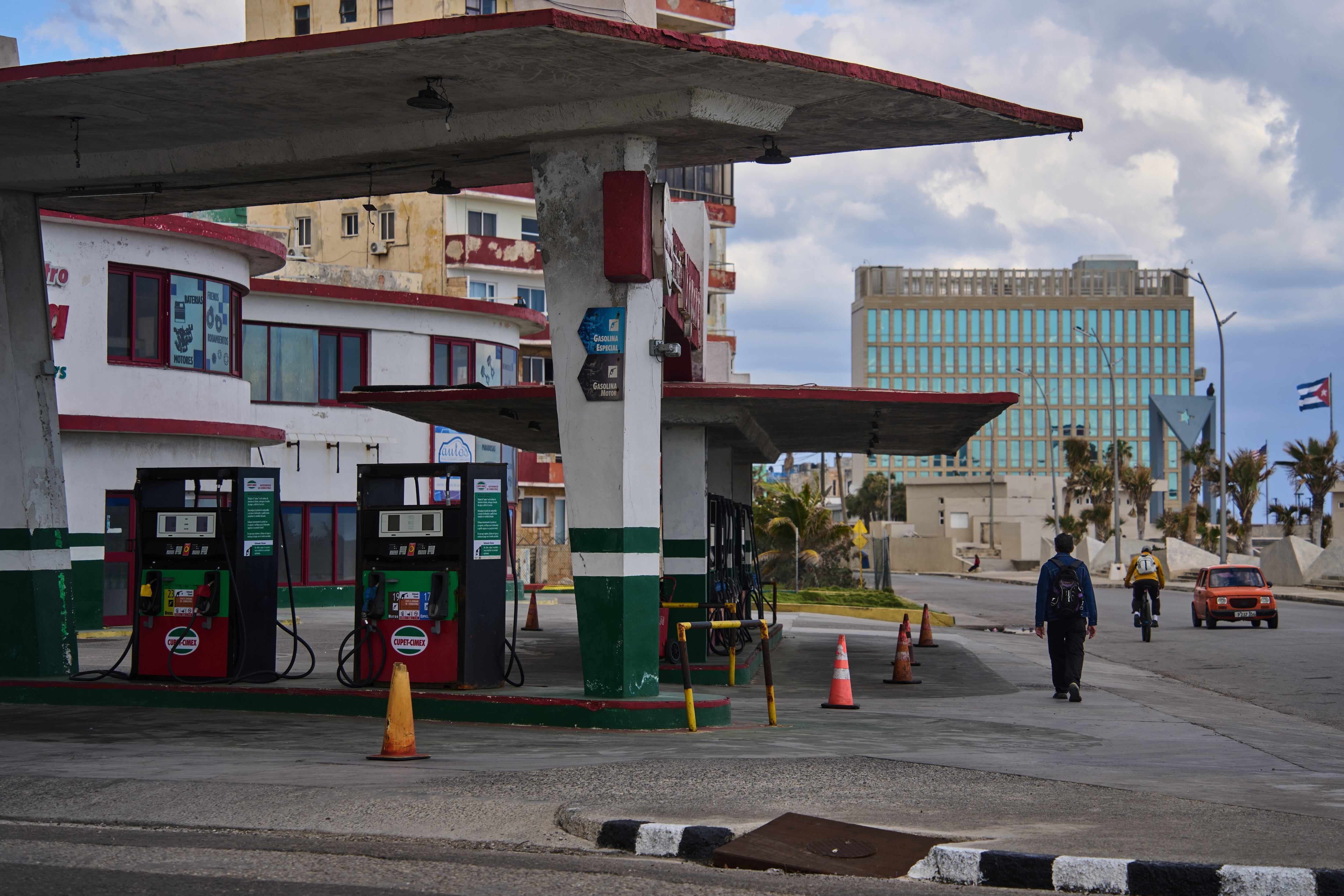 Un hombre pasa junto a una gasolinera sin combustible, ubicada cerca de la embajada de Estados Unidos (al fondo), el sábado 7 de febrero de 2026, en La Habana, Cuba (AP Foto/Ramón Espinosa)