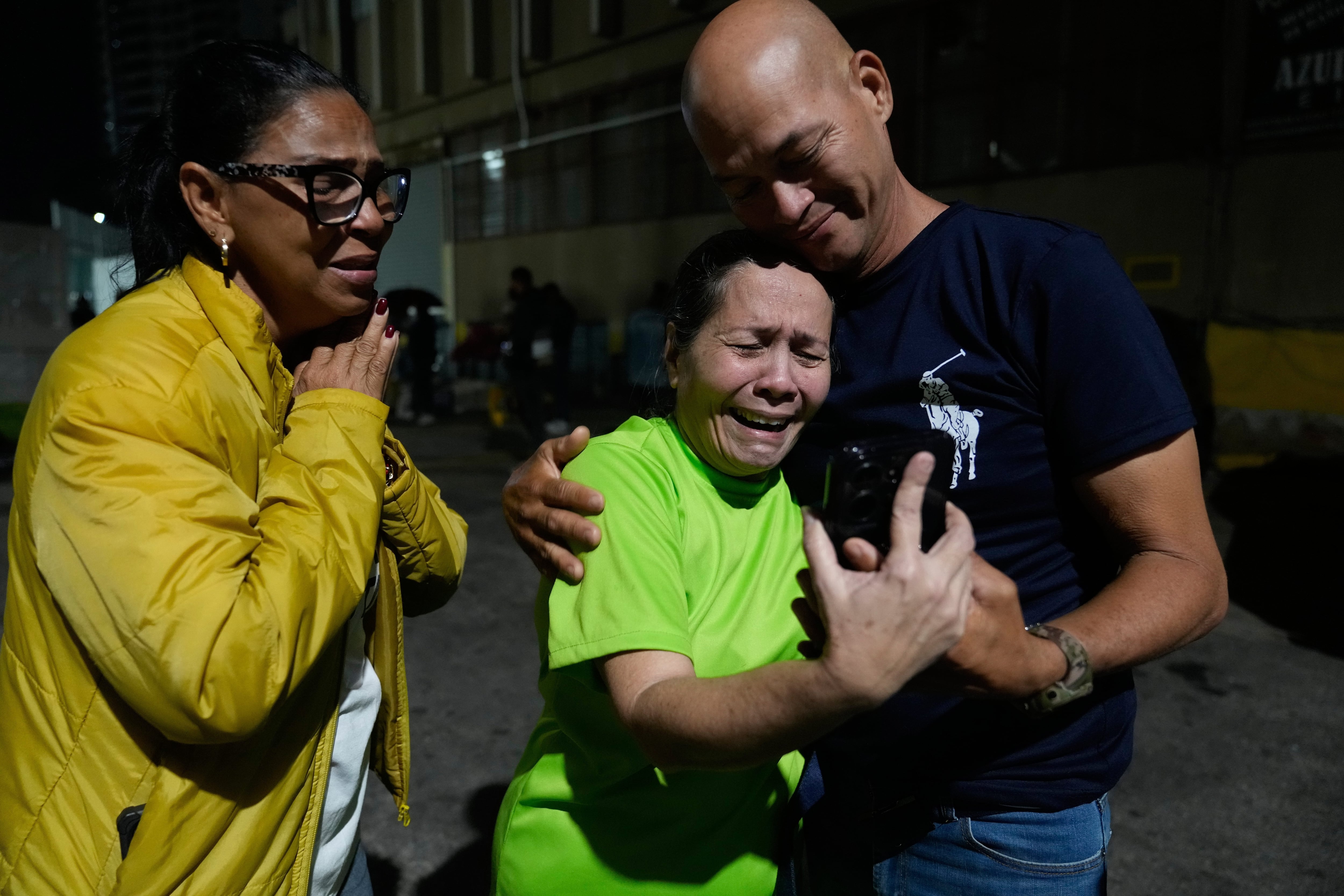 Morelba Delgado, en el centro, habla con un familiar por celular tras ser liberada del centro de detención Zona 7 de la Policía Nacional Bolivariana (AP Foto/Ariana Cubillos)