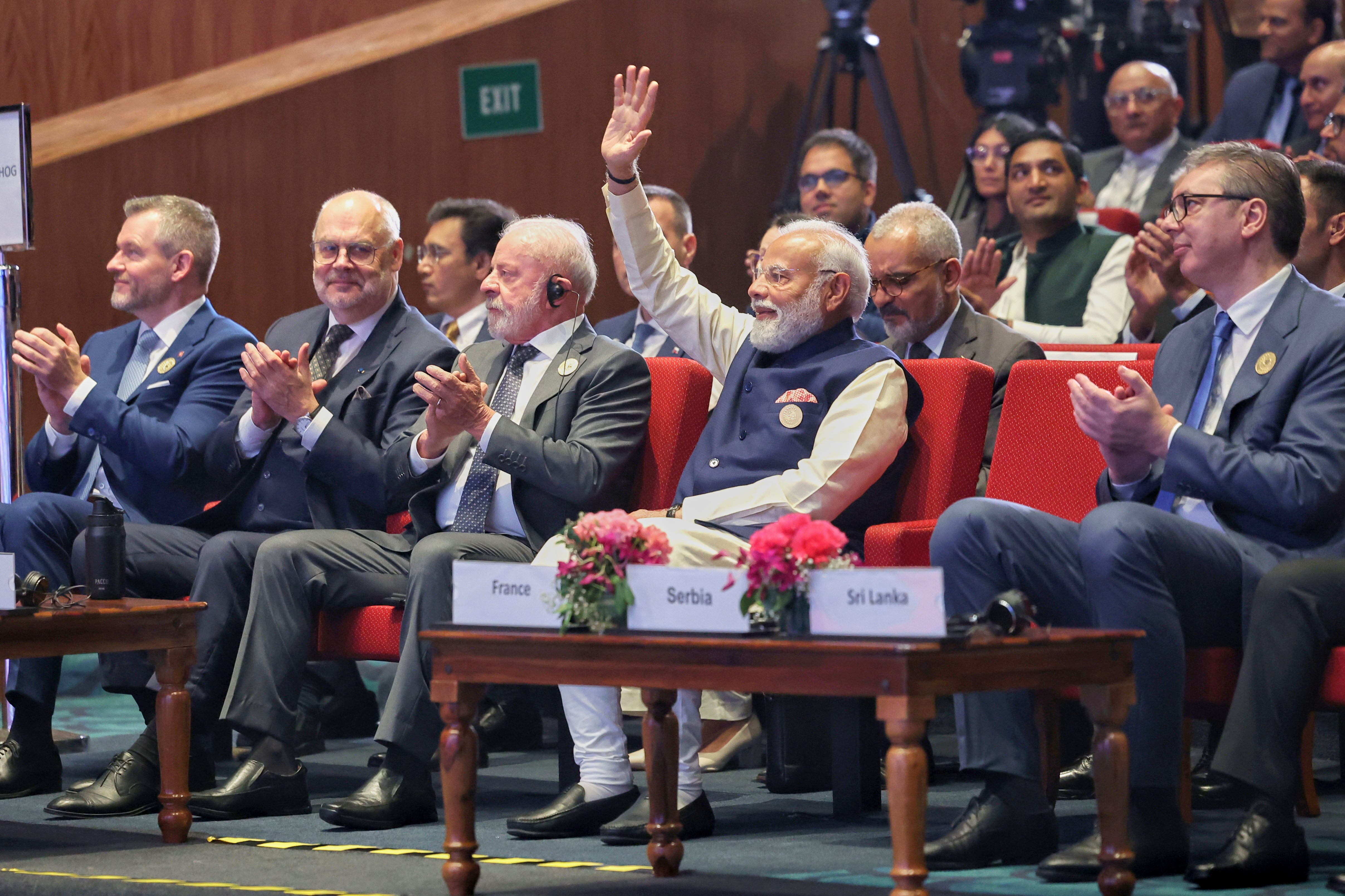El primer ministro de India, Narendra Modi (centro), alza para mano para saludar mientras otros mandatarios internacionales aplauden durante una cumbre sobre inteligencia artificial en Nueva Delhi, India. (Oficina del primer ministro de India vía AP)