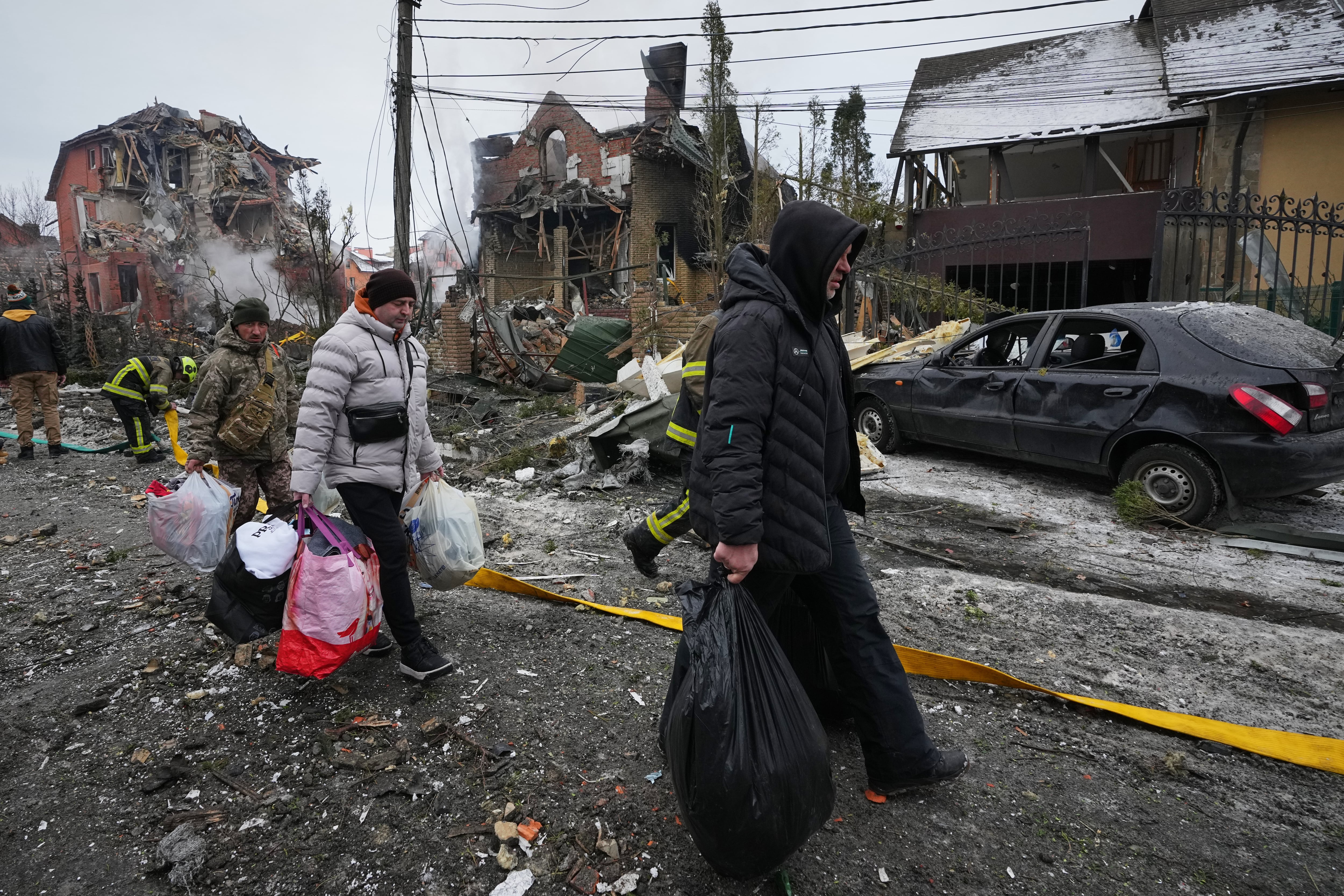 Residentes abandonan sus hogares con sus pertenencias tras un ataque de drones ruso que dañó edificios en Kiev, el domingo 22 de febrero, cuando las temperaturas rondaban los -10°C. (AP Foto/Sergei Grits)