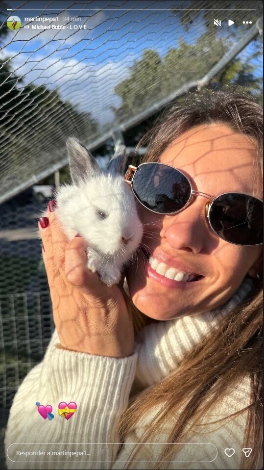 Pampita, sonriente y con gafas de sol, posa con un adorable conejo blanco y gris en sus brazos, posiblemente en una celebración de San Valentín compartida con Martín Pepa