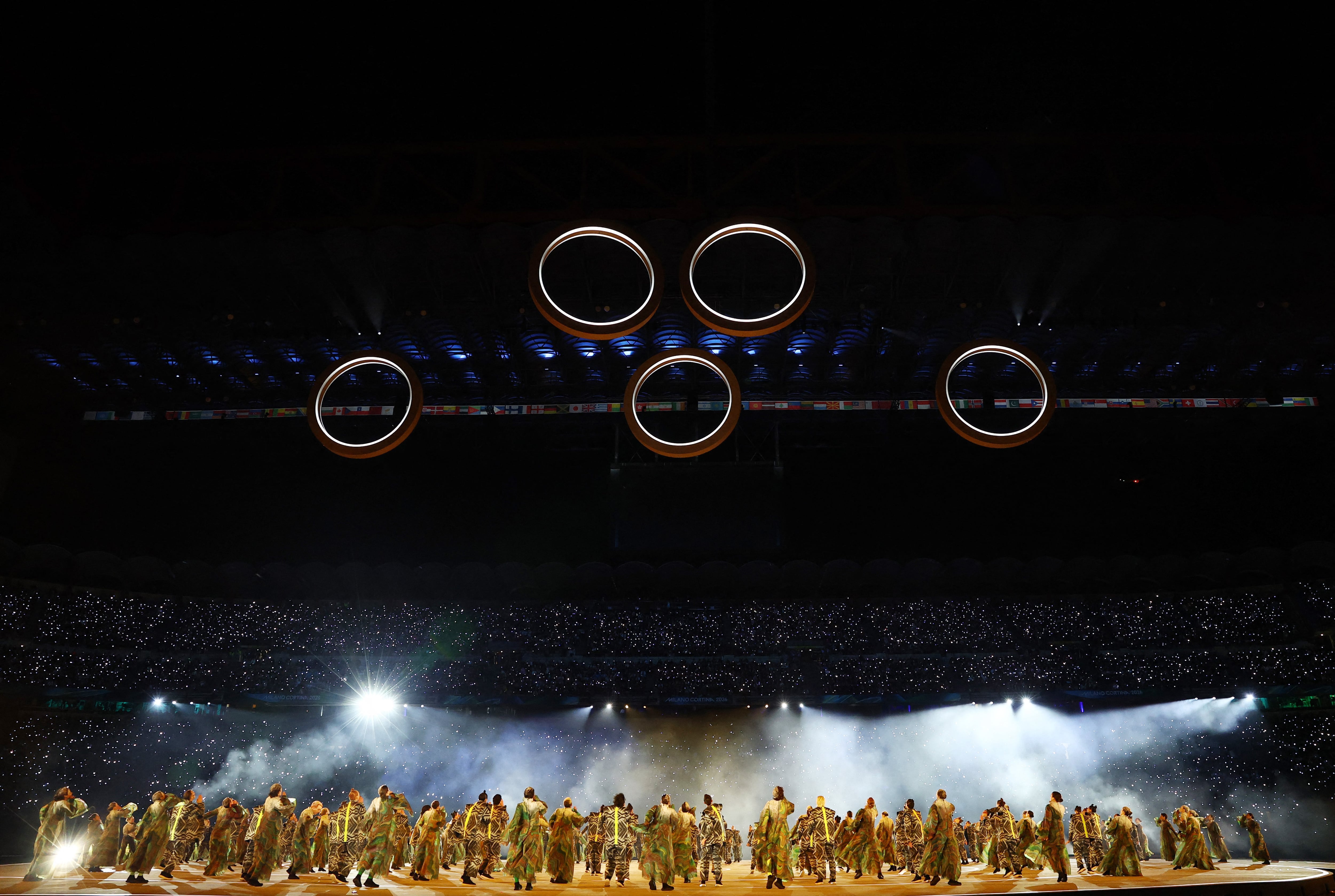 El instante previo a que queden armados los cinco anillos en su adecuada ubicación y la expectativa de los bailarines en el césped (Crédito: Reuters/Yves Herman)