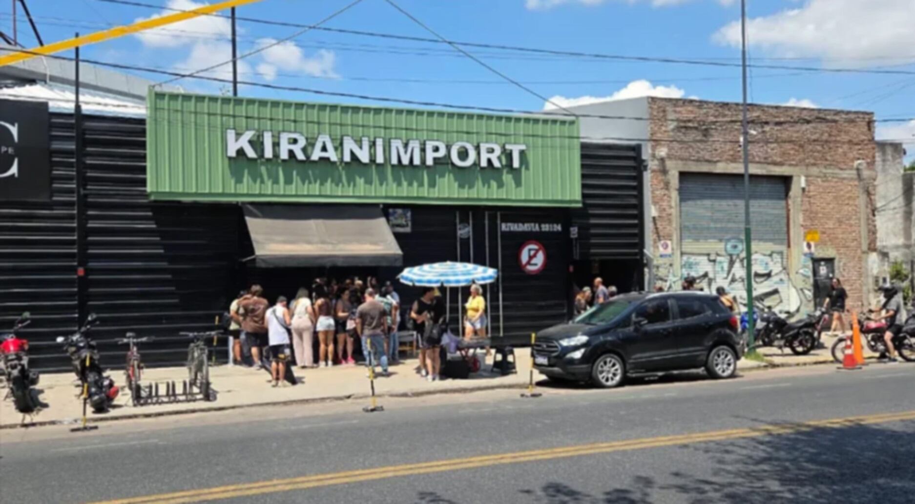 Vista exterior de la importadora Kiranimport en Ituzaingó, donde ocurrió un robo millonario, con personas y vehículos en la calle bajo un cielo azul. (Primer Plano On Line)