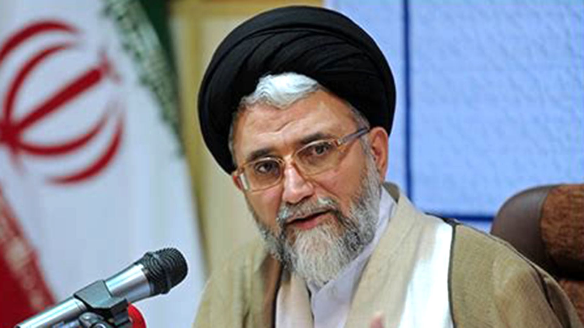 Ismail Khatib, jefe de inteligencia de Irán, se dirige a la prensa o a una audiencia, con la bandera iraní visible al fondo.