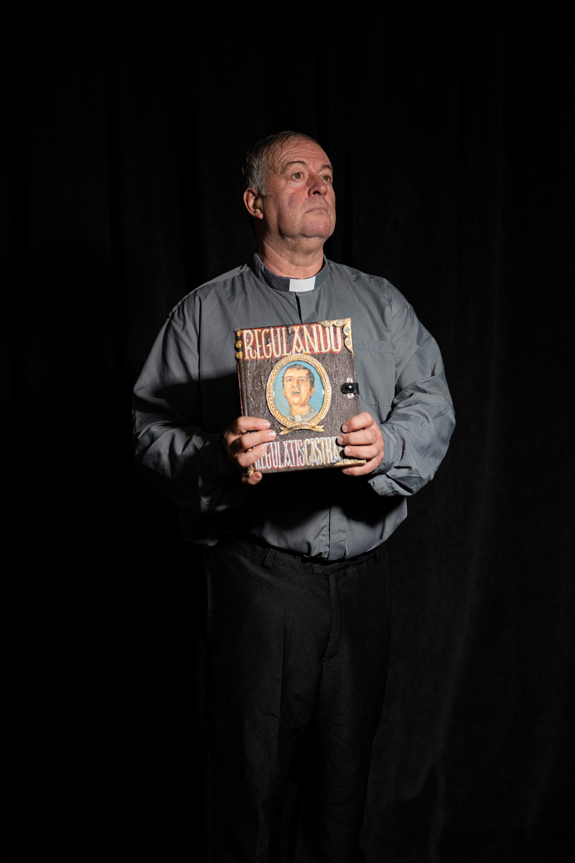 El actor y humorista Fabio Alberti posa como su popular personaje Peperino Pómoro, vestido con sotana y sosteniendo el libro 