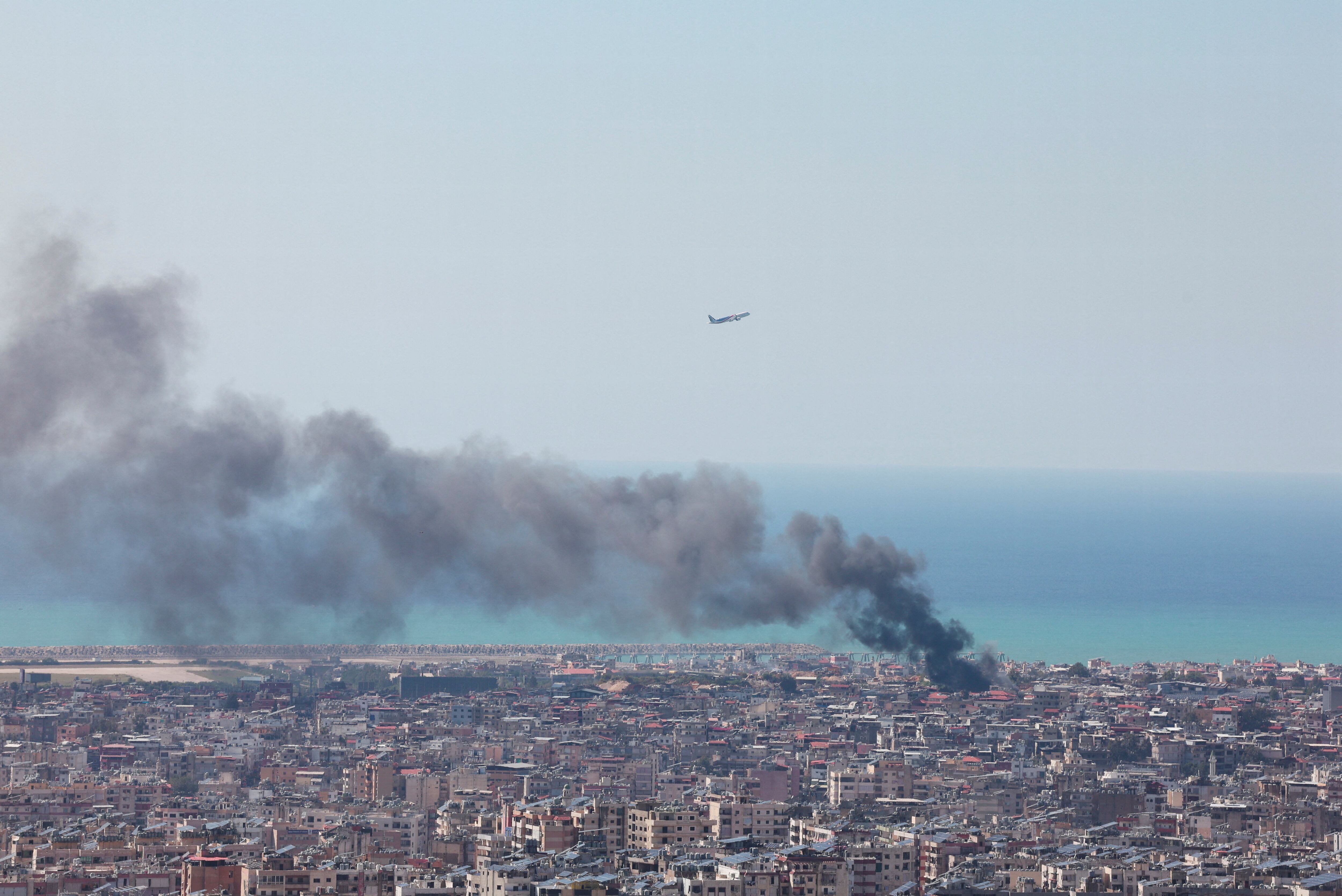 Un avión cruza el cielo de Beirut mientras se observan los efectos de un ataque aéreo en la ciudad (REUTERS/Mahmoud Hassano)
