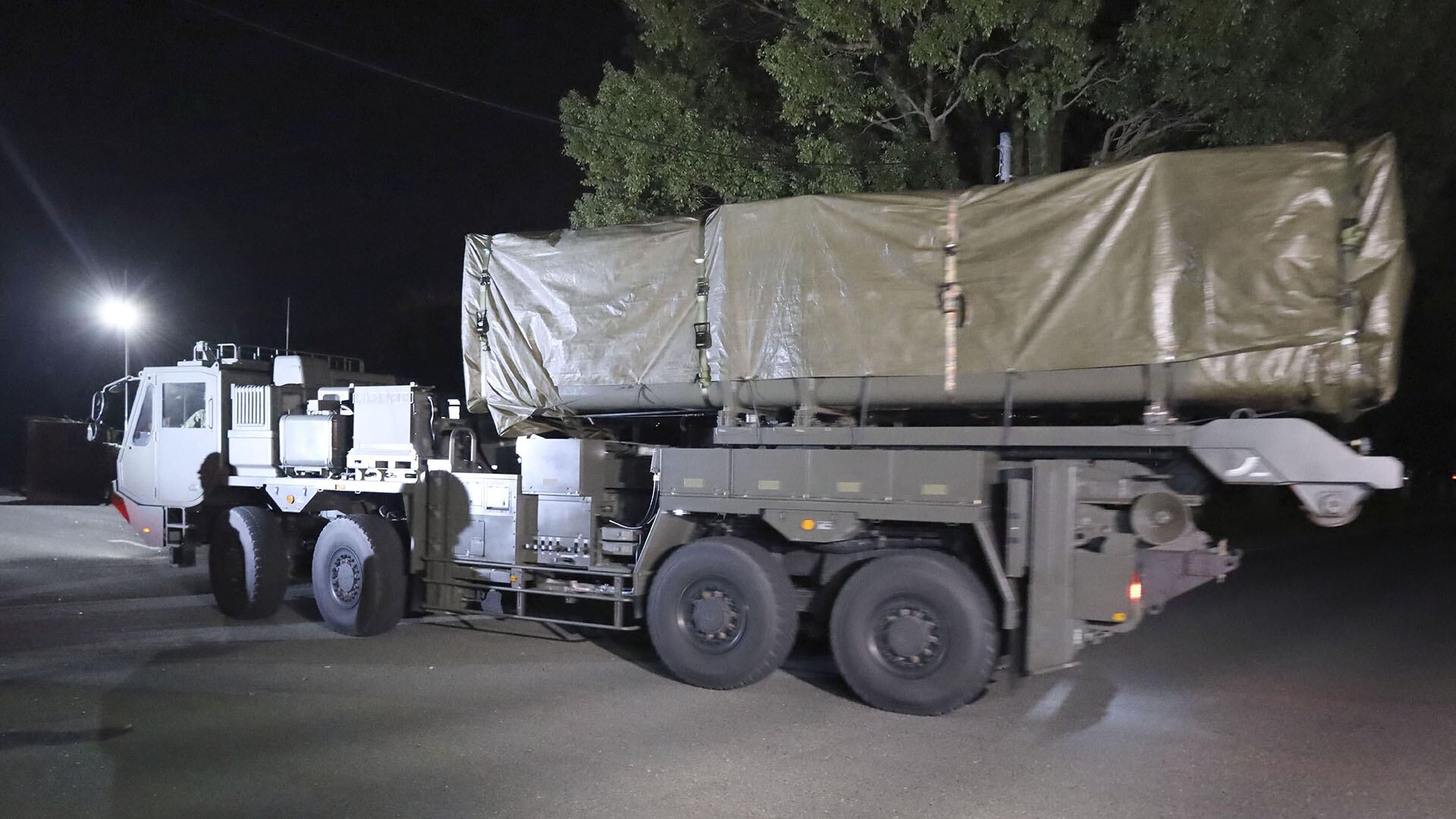 Un vehículo de transporte de la Fuerza Terrestre de Autodefensa de Japón se mueve con equipo camuflado en el Campamento Kengun bajo la oscuridad de la noche.