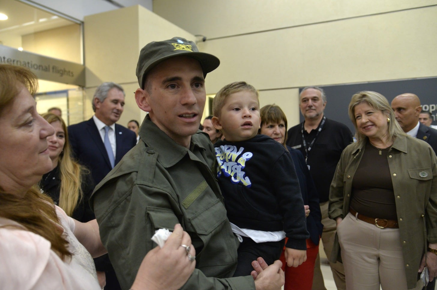 El oficial Nahuel Gallo, reconocido por su servicio, comparte un tierno momento con su hijo durante un encuentro público, rodeado de asistentes.
