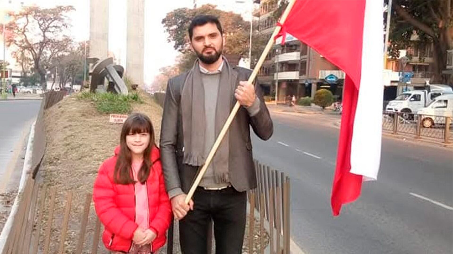 Francisco Condorí y su hija posan con la bandera de Polonia en las calles de San Miguel de Tucumán, de donde son oriundos