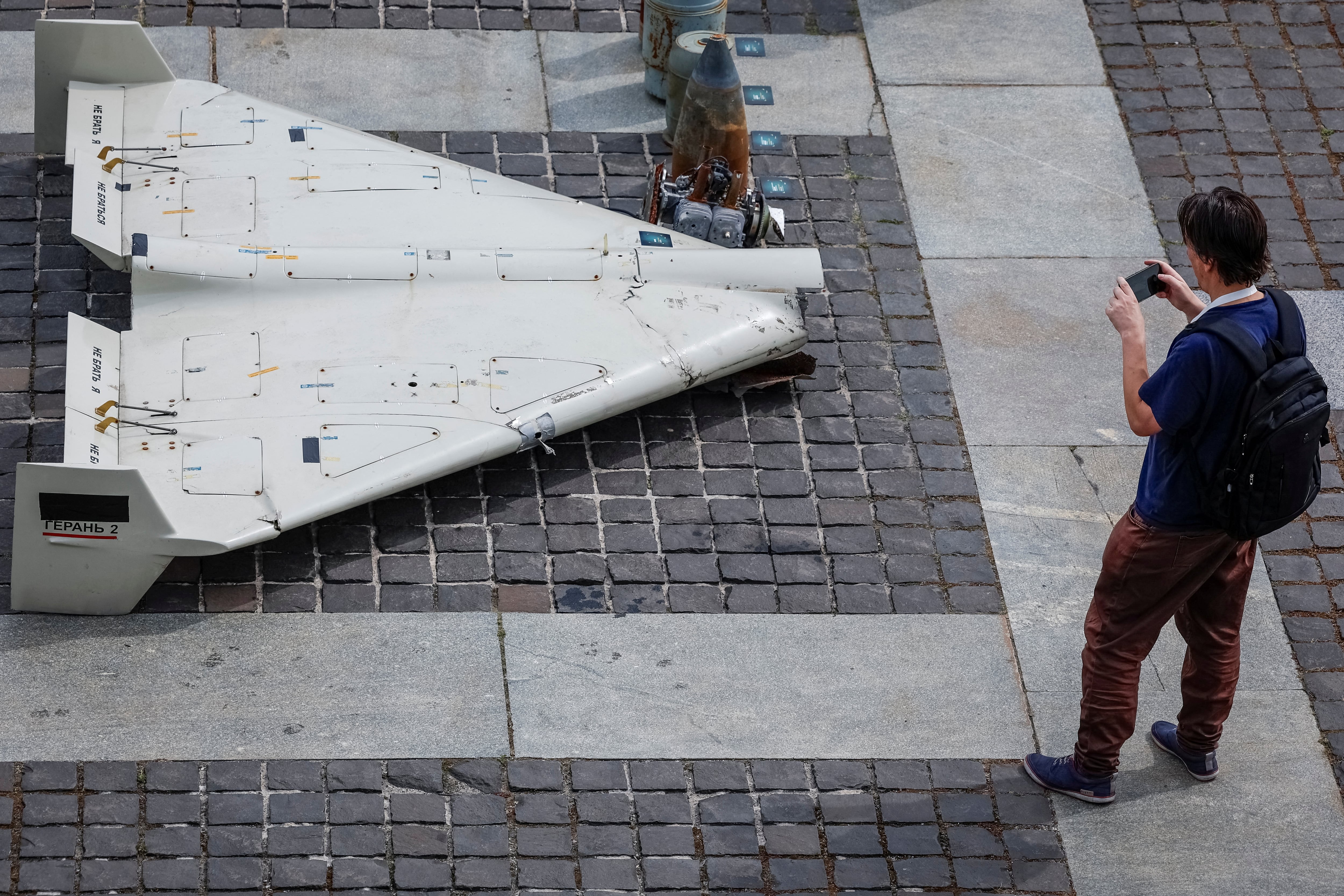 Un hombre toma una fotografía de partes de un vehículo aéreo no tripulado (VANT) Shahed-131/136 de fabricación iraní (REUTERS/Alina Smutko/Archivo)
