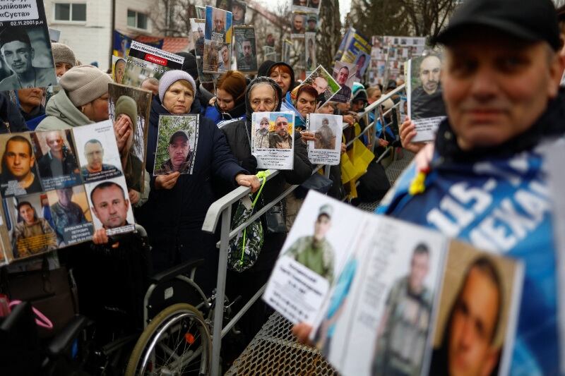 La gente sostiene retratos de sus familiares, prisioneros de guerra ucranianos (POW), con la esperanza de que sean reconocidos por otros prisioneros de guerra, que regresan después de un intercambio (REUTERS/Valentyn Ogirenko)