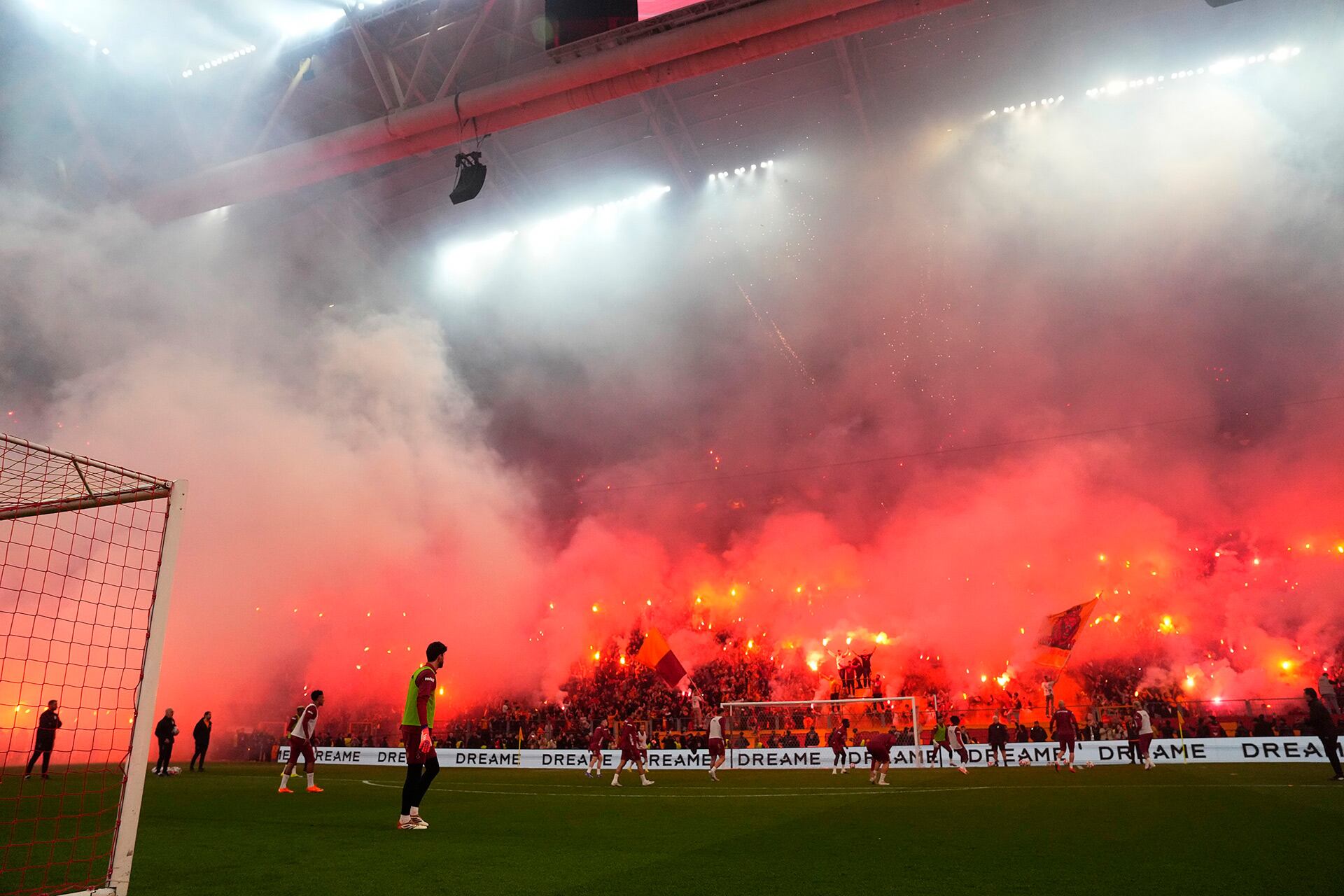 Aficionados del Galatasaray iluminan el estadio con pirotecnia y humo rojo durante un entrenamiento abierto, creando un ambiente vibrante para el equipo. (@GalatasaraySK)