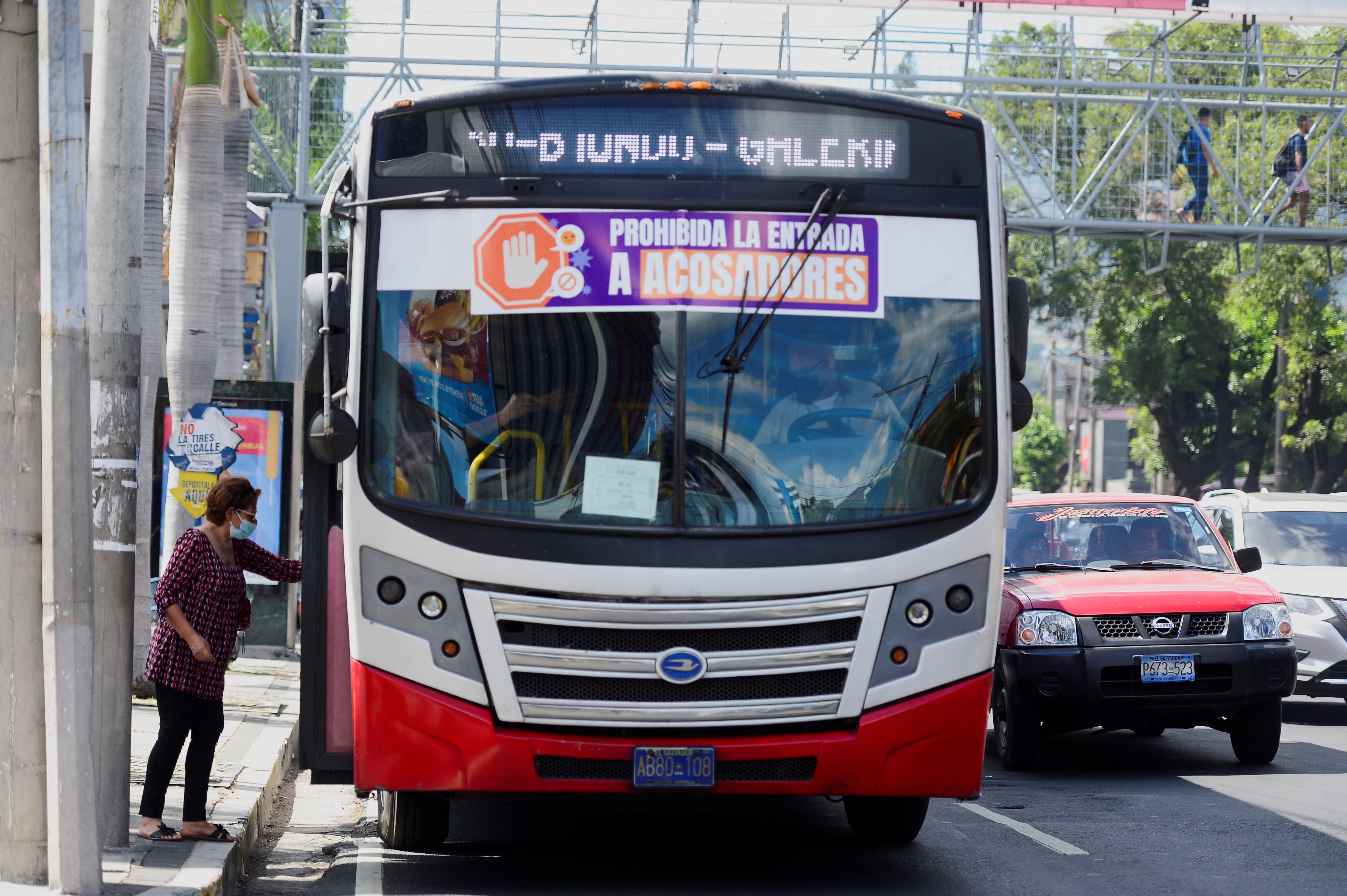 A woman boards a bus with a sign reading: 