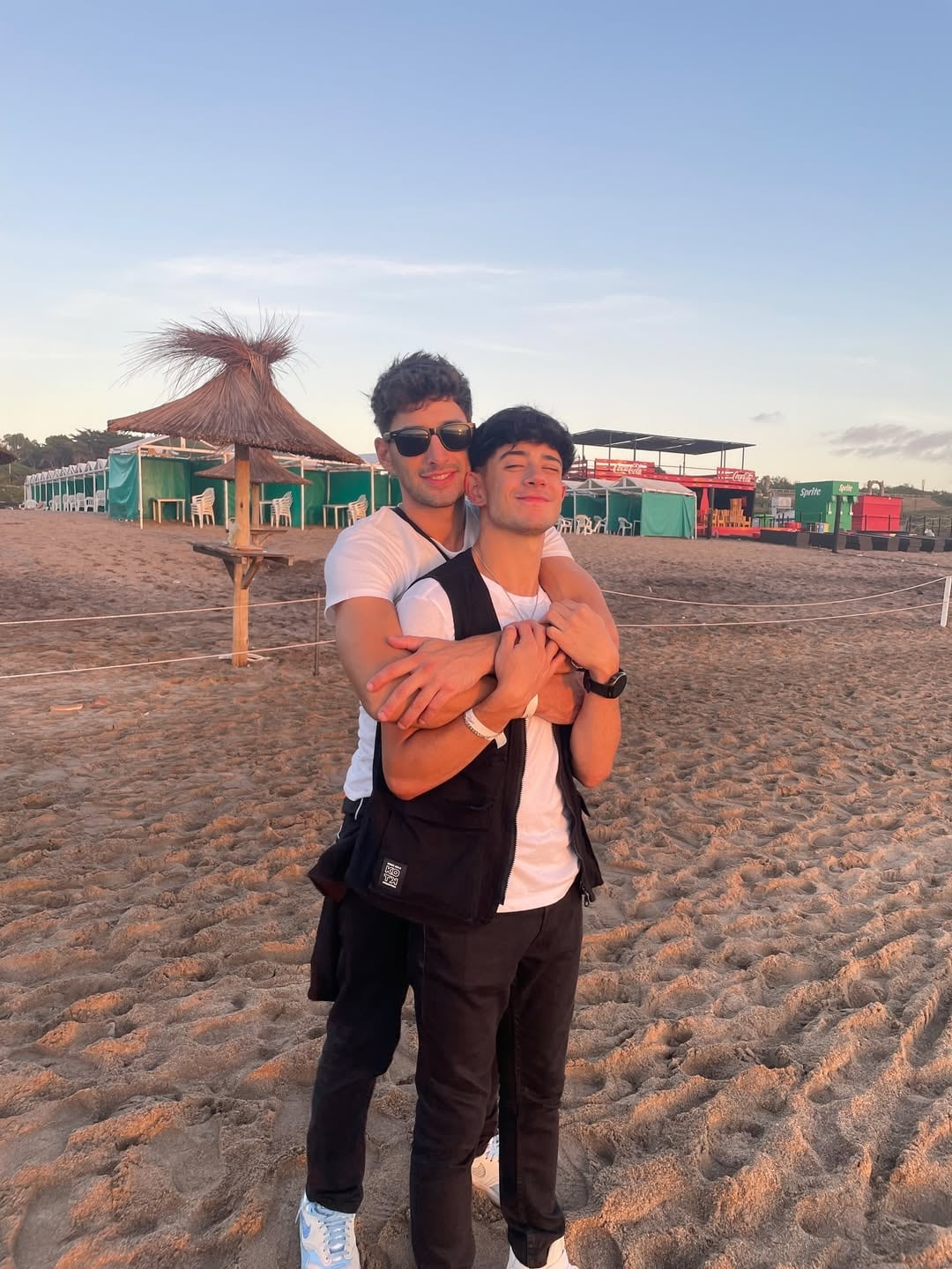 Kevsho compartiendo un tierno momento con su pareja durante sus vacaciones en la playa, disfrutando del atardecer