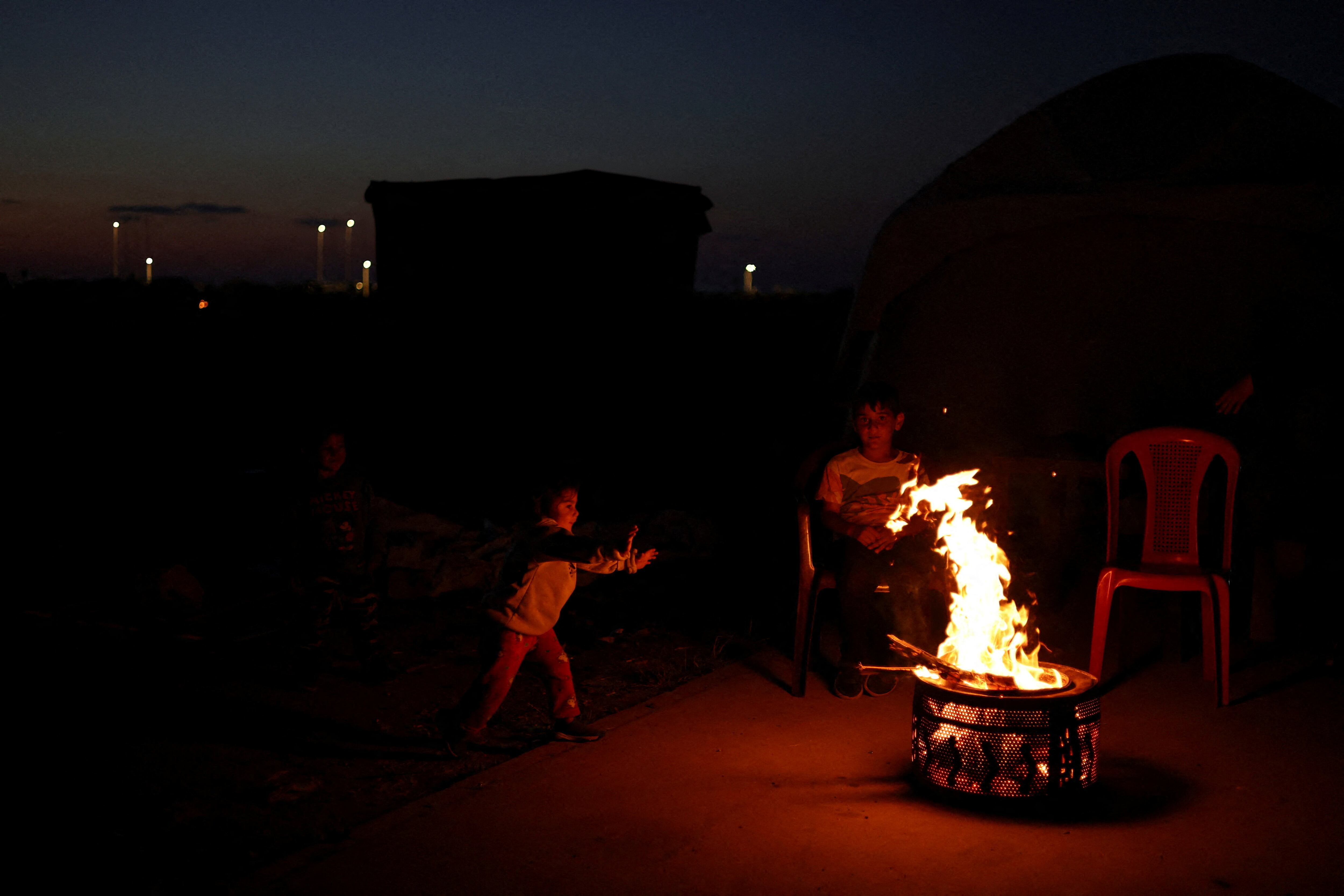 Niños desplazados juegan alrededor de una hoguera en un campamento improvisado, en medio de un alto el fuego (REUTRS/Saleh Salem)