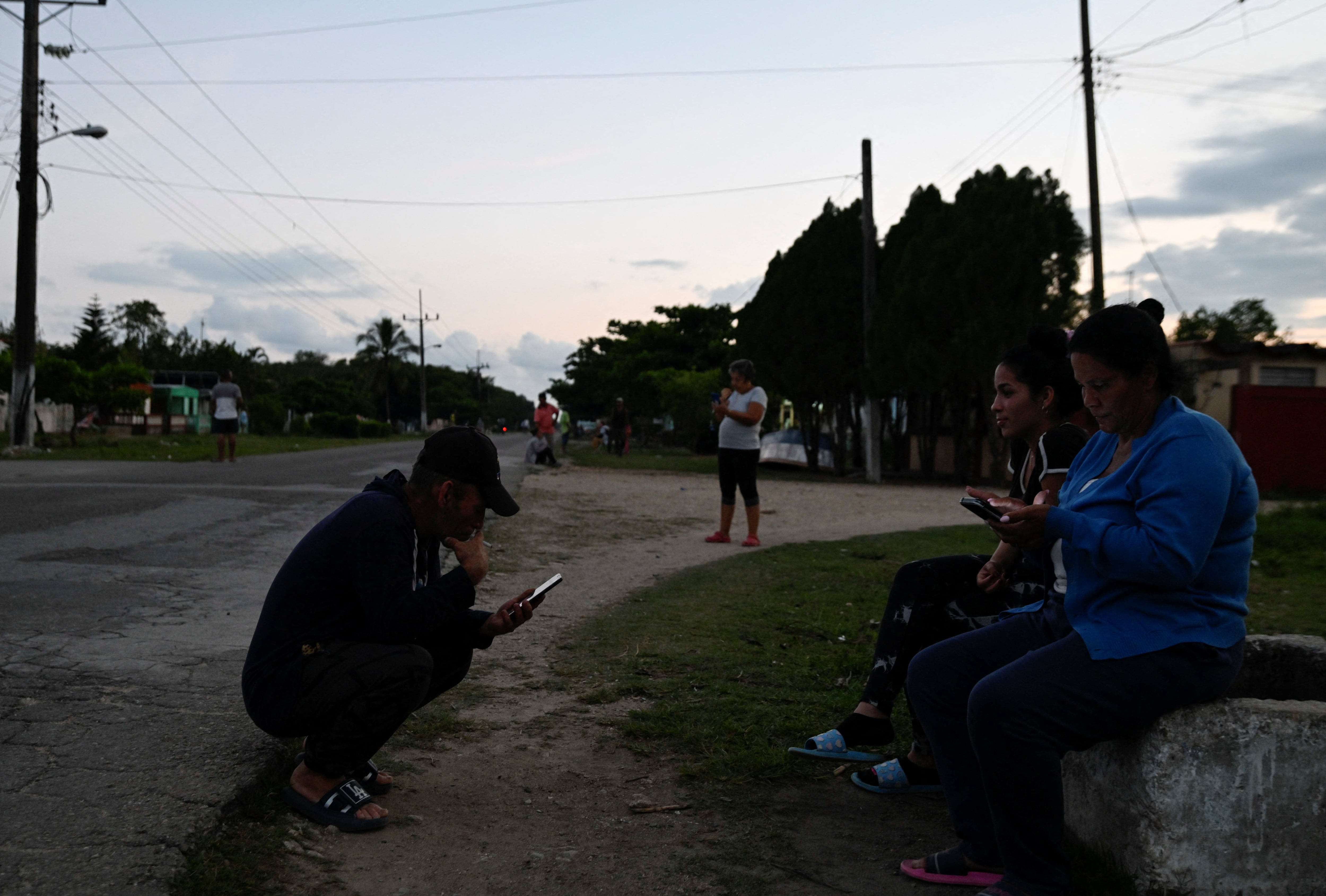La gente se congrega en la calle buscando servicio telefónico e internet durante un apagón, el 7 de abril de 2026 (REUTERS/Norlys Perez)