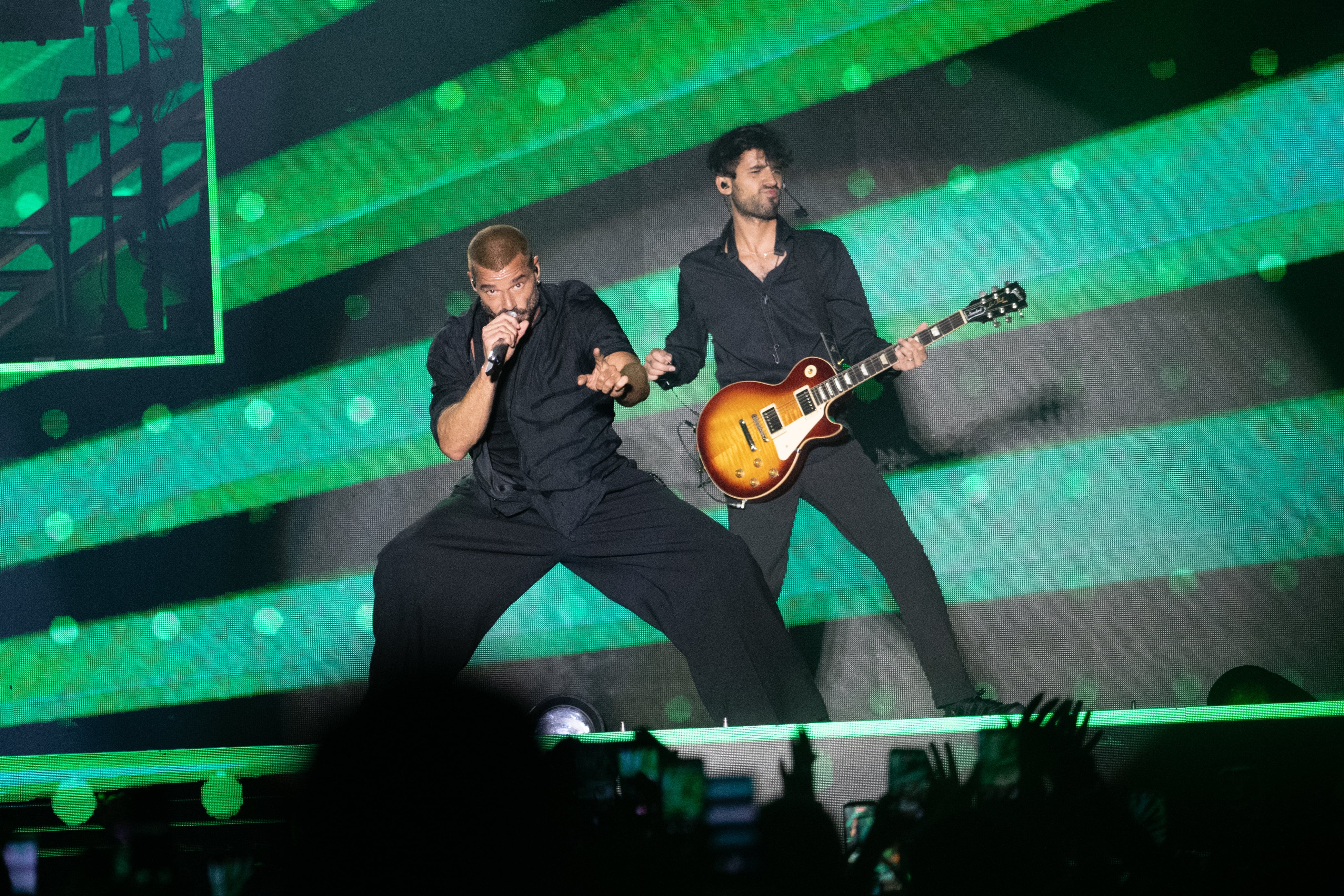 El intérprete cantando acompañado por su guitarrista, en una puesta visual dominada por luces verdes