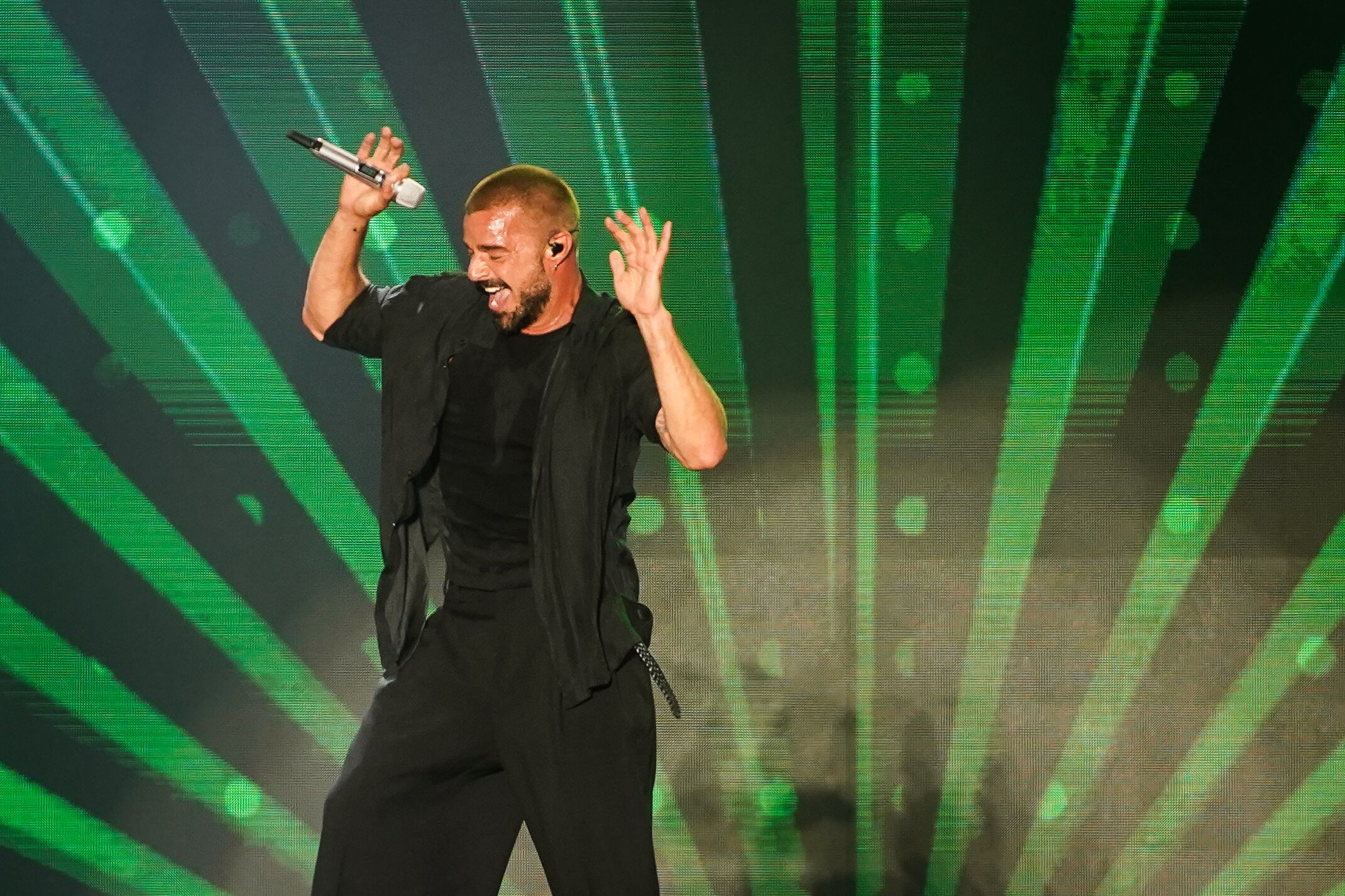 Entre luces verdes, el ídolo latino celebra cada compás con gestos vibrantes