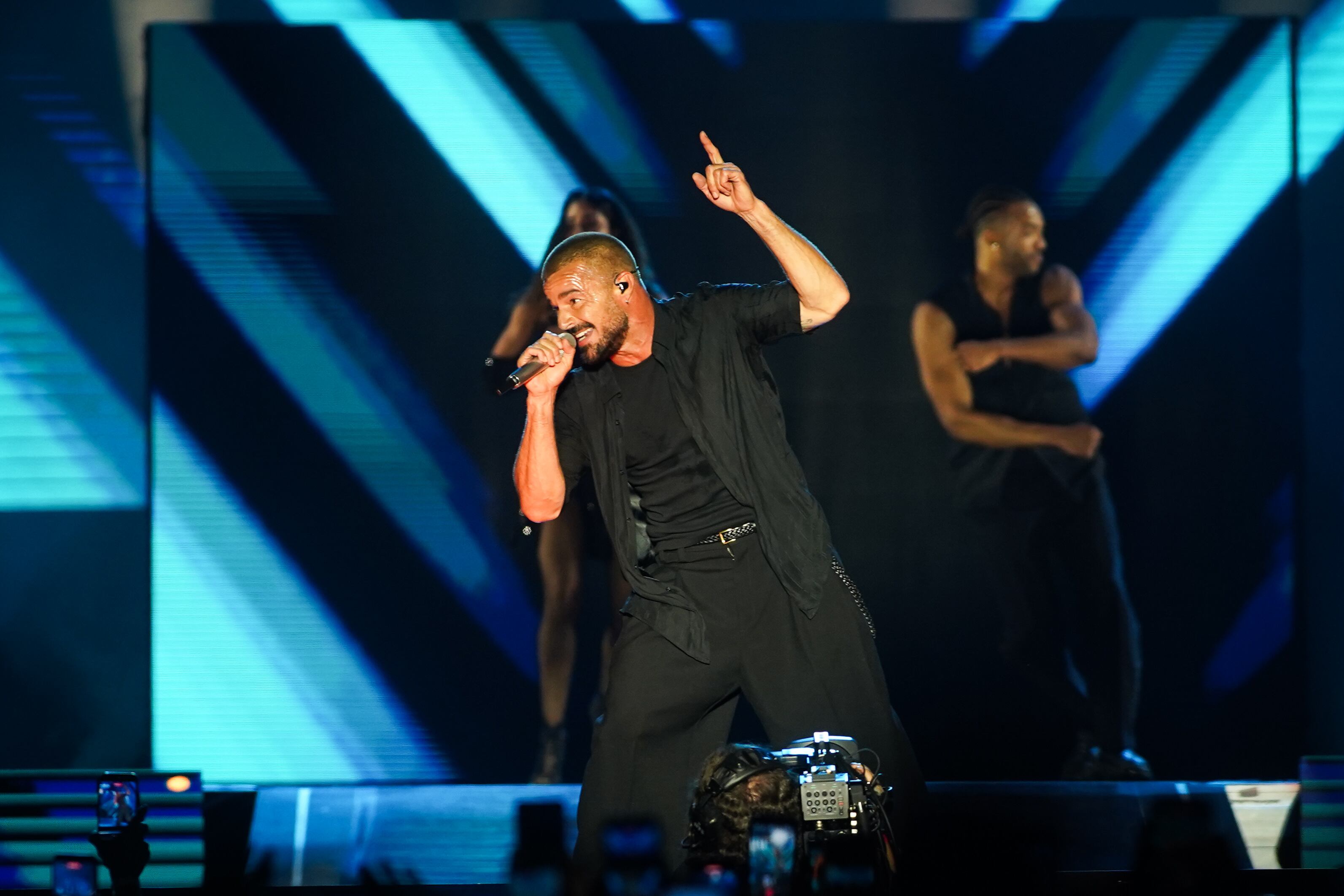 Con gesto firme, el cantante señala al cielo mientras enciende al público