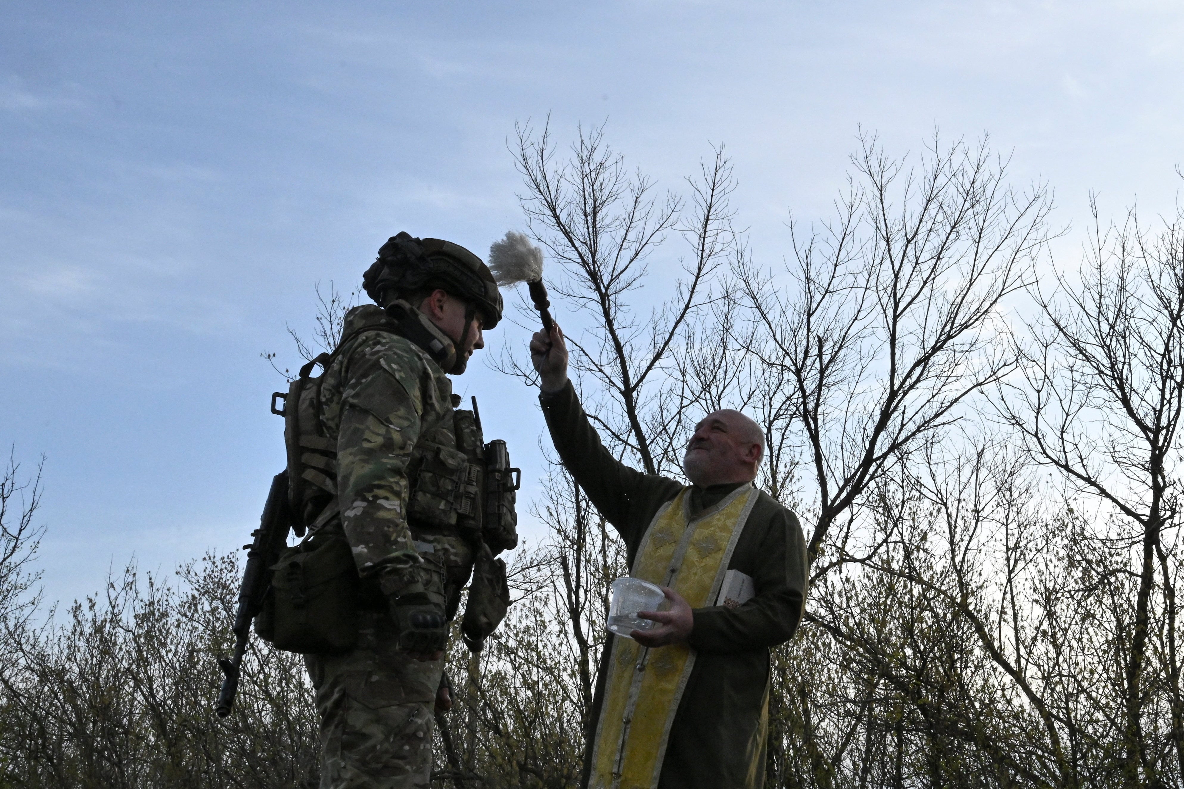 El capellán ortodoxo Stepan rocía agua bendita sobre un miembro del Batallón de Operaciones Especiales de la Policía Nacional de la región de Zaporizhzhia, Ucrania (REUTERS)