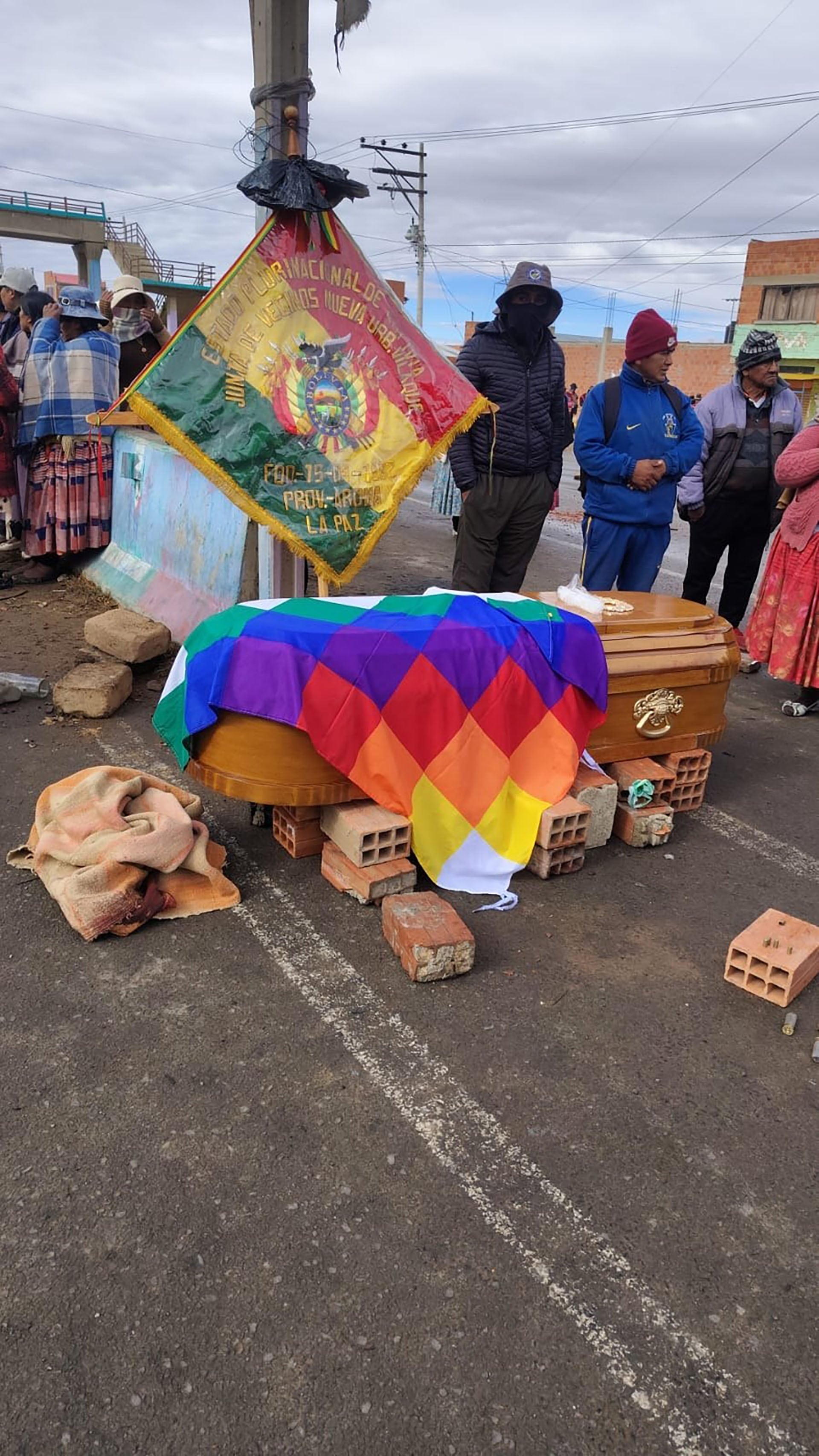 El ataúd de Víctor Cruz Quispe, cubierto con la bandera Wiphala, es velado por la comunidad sobre una calle en Bolivia, exigiendo justicia en medio del dolor.
