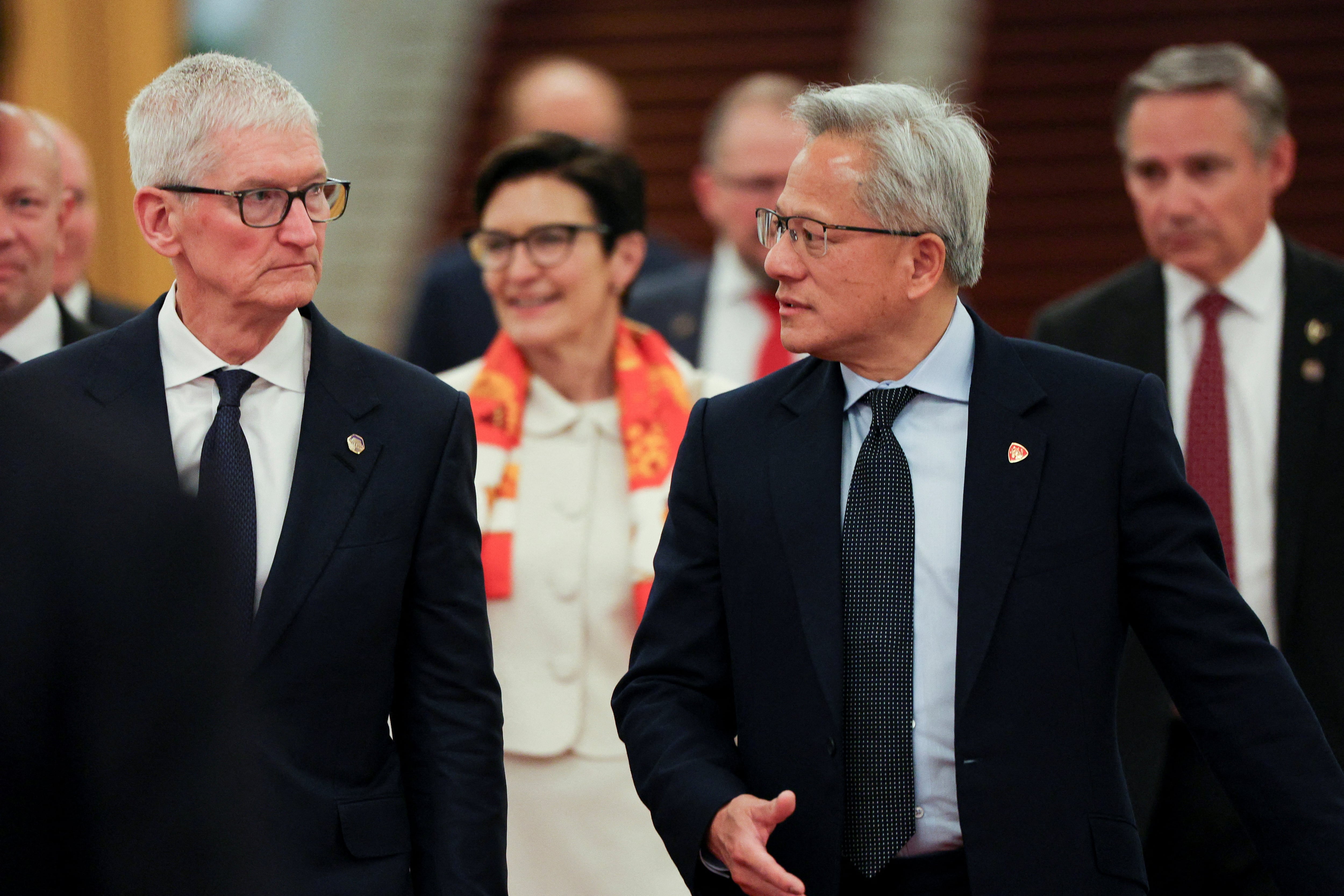 El director ejecutivo de Nvidia, Jensen Huang, y el director ejecutivo de Apple, Tim Cook, llegan a la reunión entre el primer ministro chino, Li Qiang, y representantes empresariales estadounidenses, en el Gran Salón del Pueblo en Pekín, China, el 14 de mayo de 2026. REUTERS/Go Nakamura/Pool