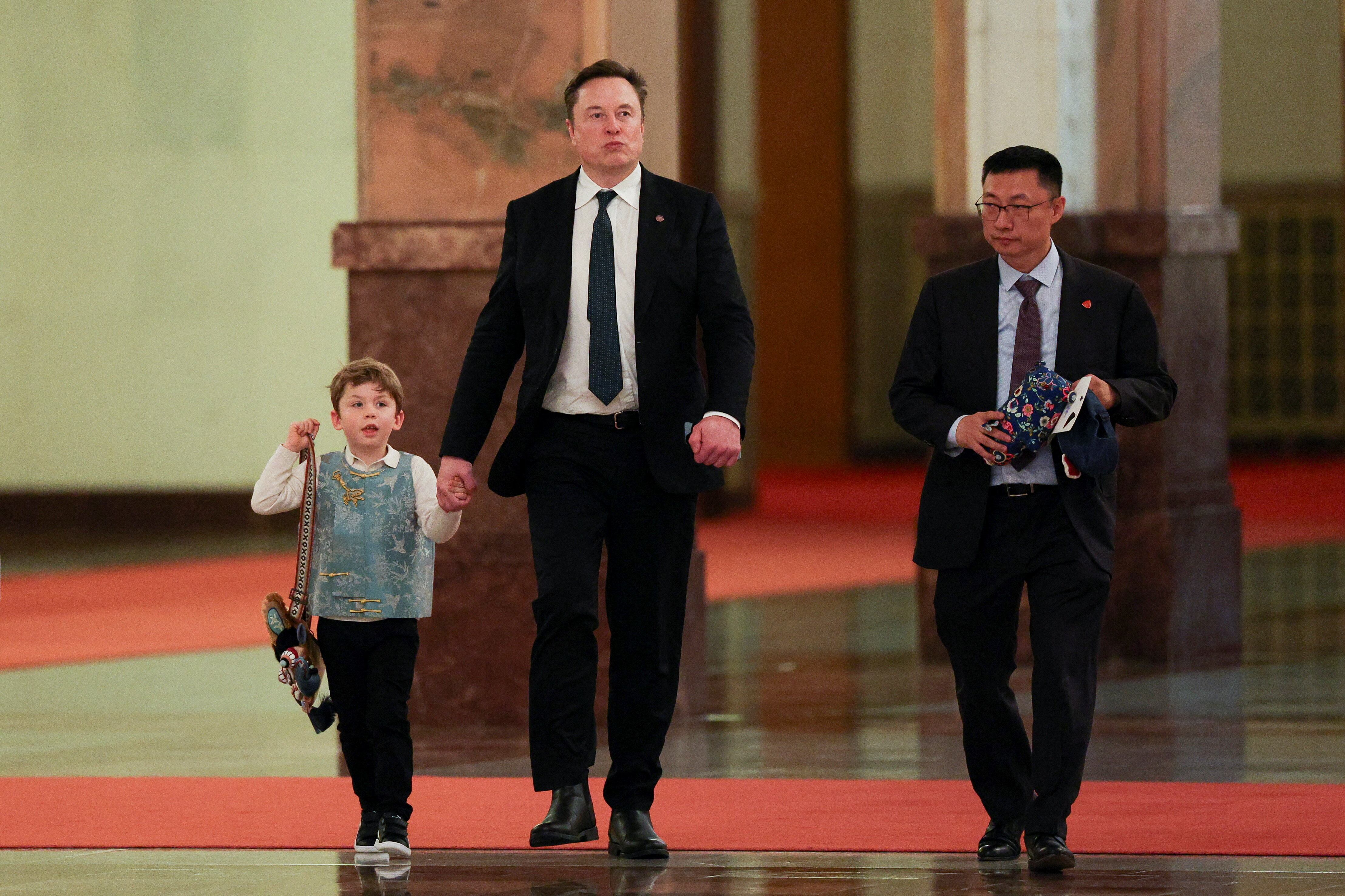 Elon Musk, CEO de Tesla, y su hijo X Æ A-12 caminan el día en que el primer ministro chino, Li Qiang, se reúne con directores ejecutivos estadounidenses, en Pekín, China, el 14 de mayo de 2026. REUTERS/Go Nakamura/Pool
