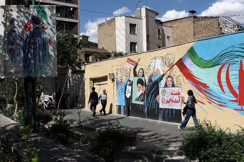 La gente camina por una calle cerca de un mural con una imagen del difunto líder dupremo de Irán, el ayatollah Alí Khamenei, en Teherán, Irán. 18 de mayo de 2026 (Majid Asgaripour/WANA vía REUTERS)
