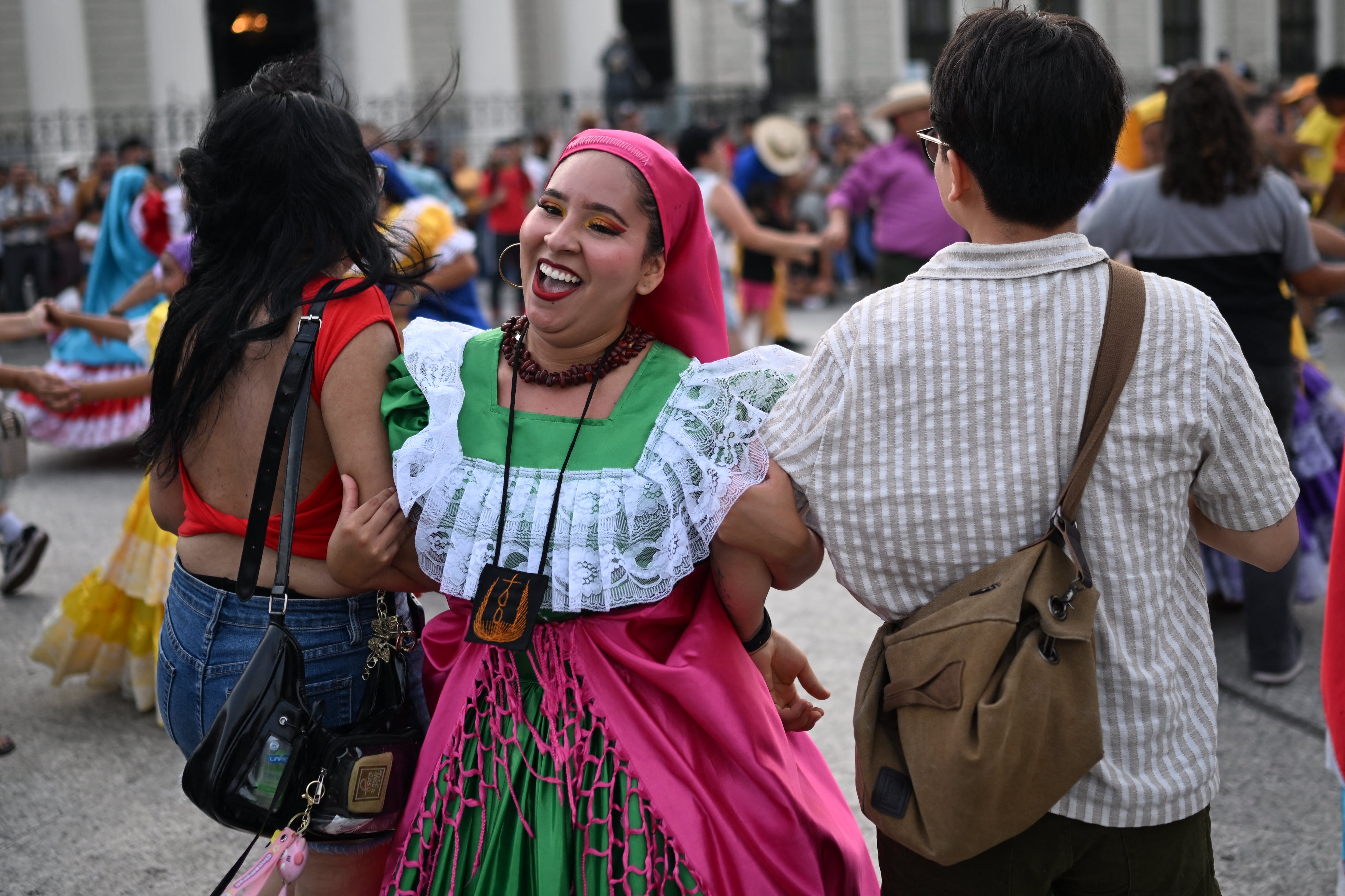 Bailarines folclóricos interactúan con turistas en el centro histórico de San Salvador, El Salvador, el 7 de mayo de 2026. (Foto de Marvin RECINOS / AFP)