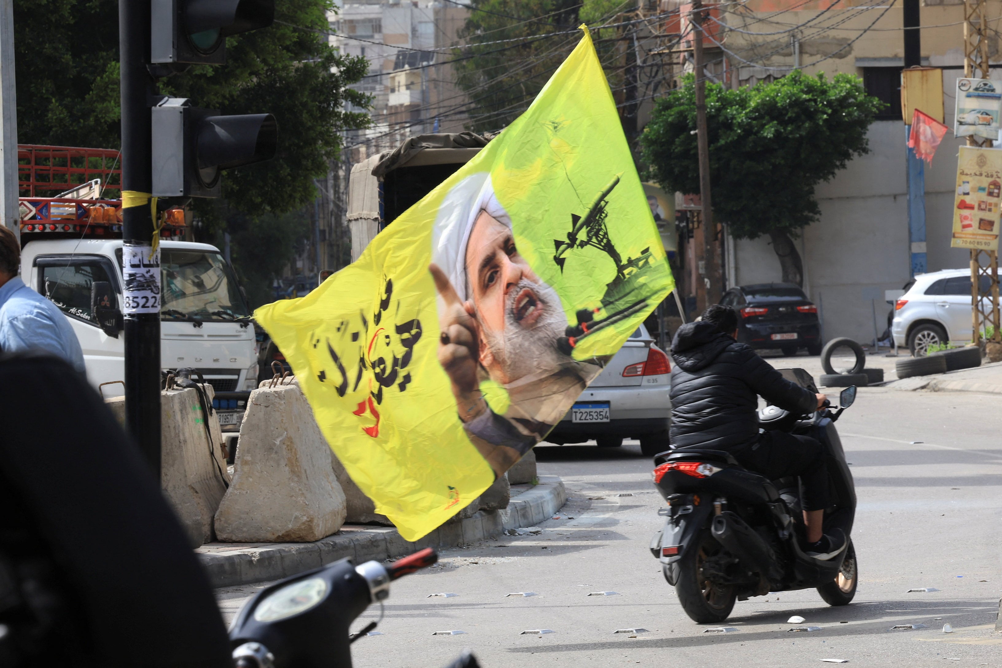 Una persona porta una bandera con la imagen del líder de Hezbollah, Naim Qassem, en los suburbios del sur de Beirut el 17 de abril de 2026, día en que entró en vigor el alto el fuego entre Líbano e Israel. Los Emiratos Árabes Unidos designaron este miércoles a 21 libaneses y organizaciones vinculados al grupo chií como terroristas. (Mohamed Azakir/Reuters)
